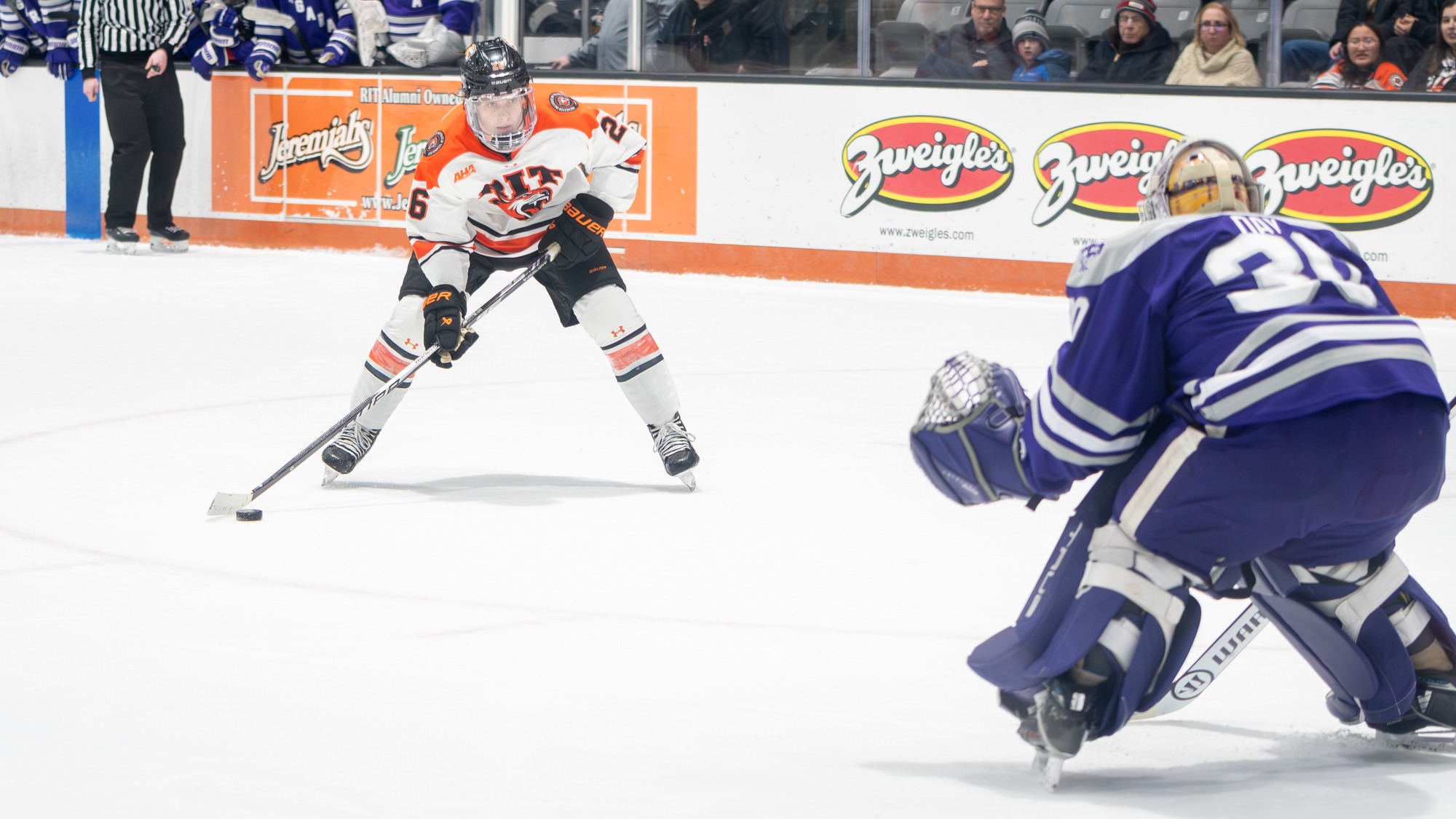 a men's hockey player getting ready to take a penalty shot on an opposing goaltender