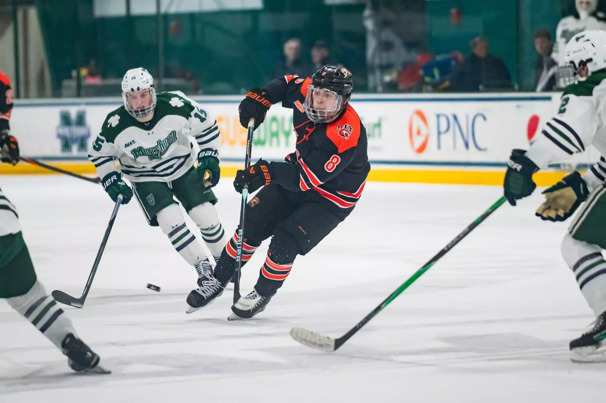 a men's hockey player skating through some defensemen with the puck