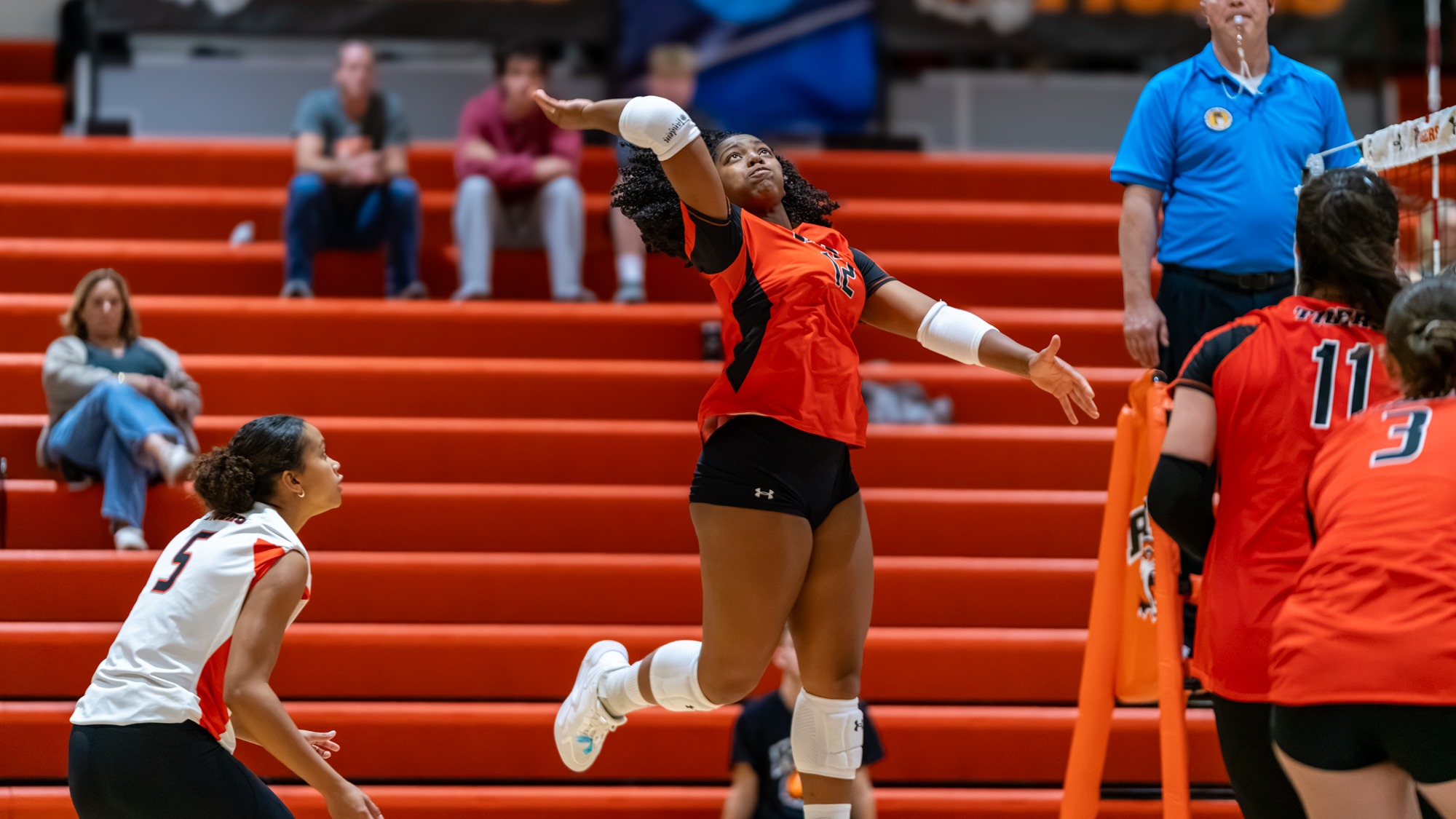 a women's volleyball player attacking a ball