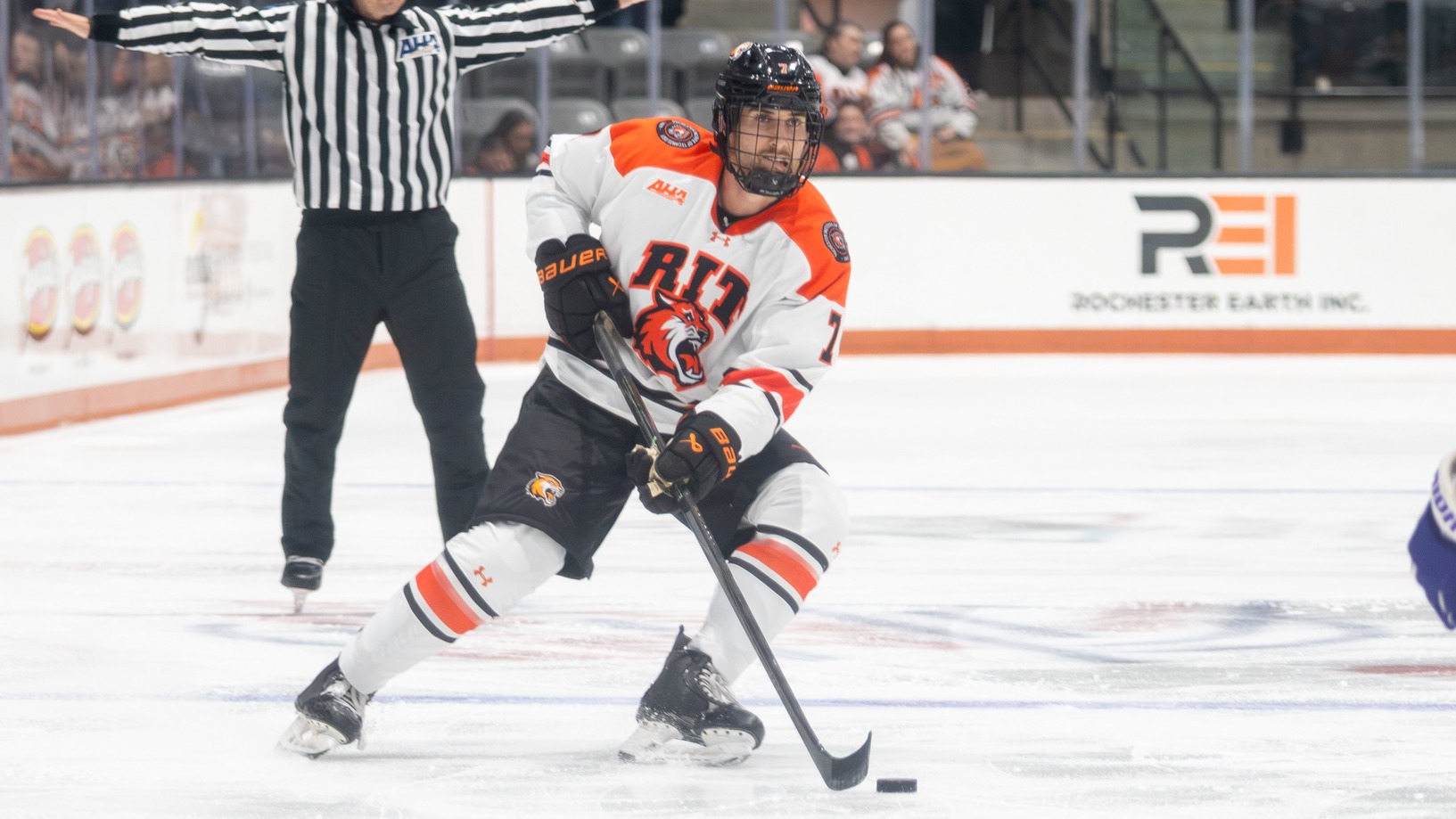 a men's hockey player skating with the puck