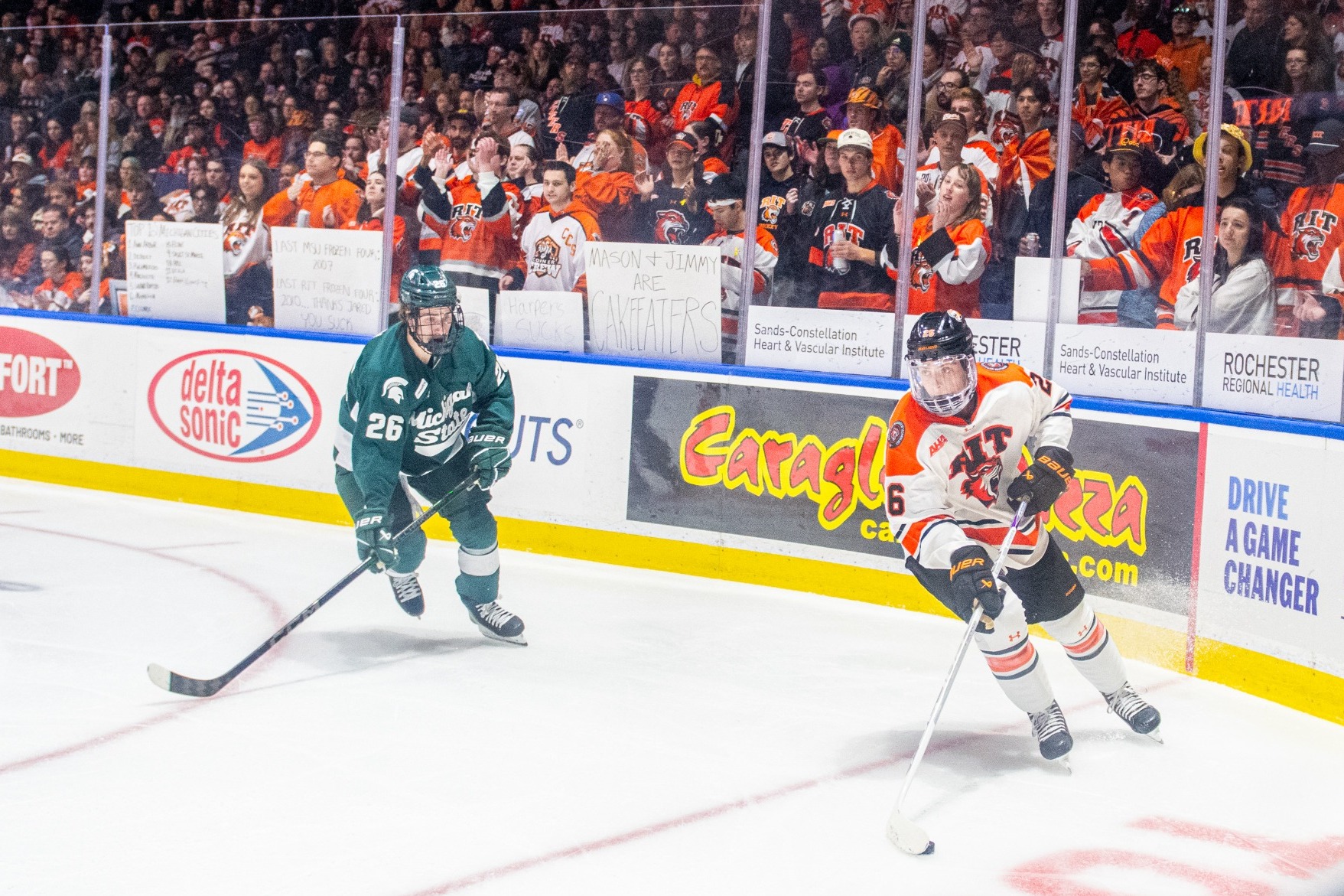 two men's hockey players skating in the corner in front of a sold out crowd of fans