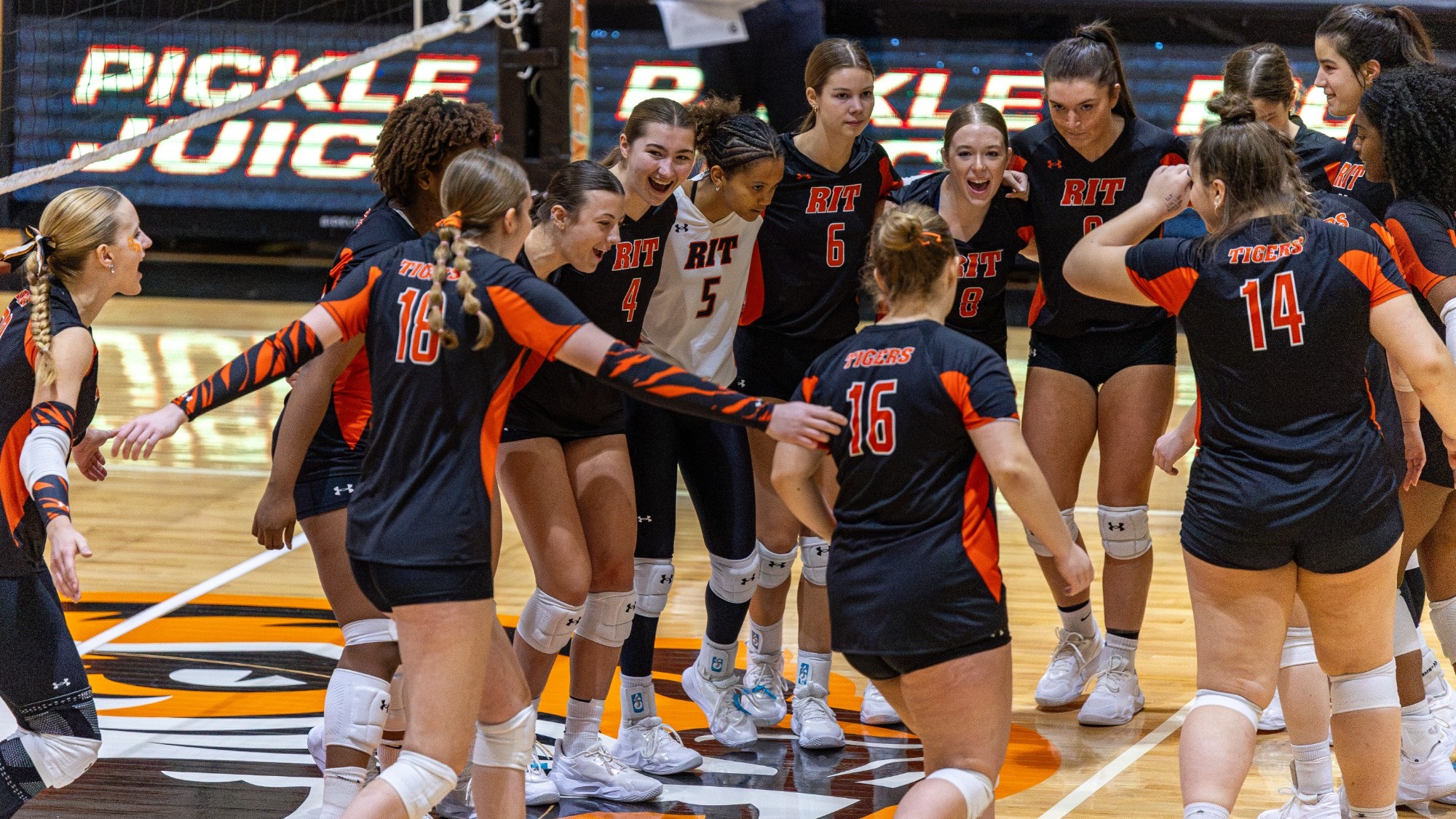 a women's volleyball team cheering before the start of a match