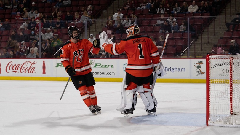 a men's hockey player high fiving his goaltender