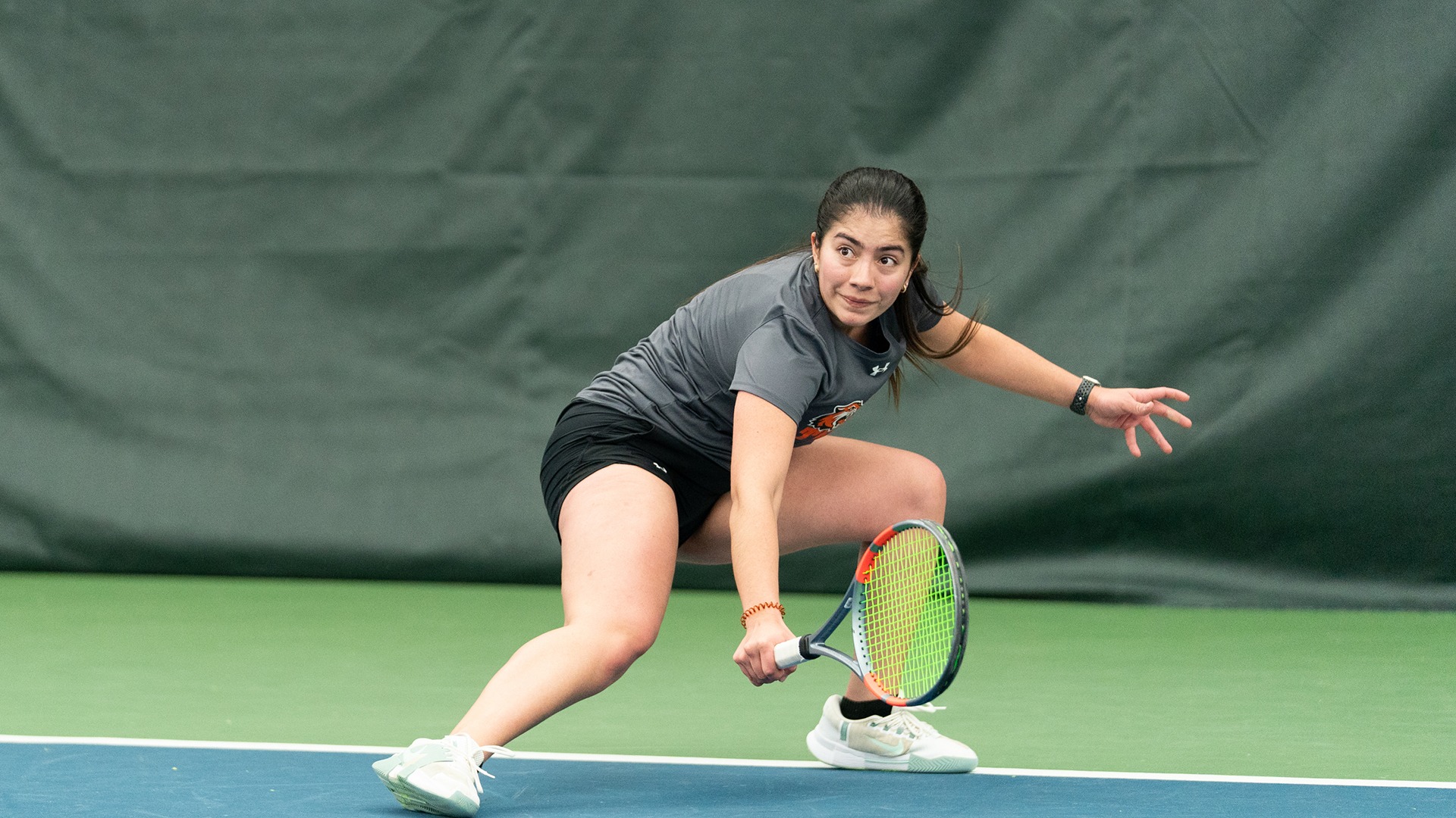 A photo of a rit women's tennis player returning a ball using her backhand