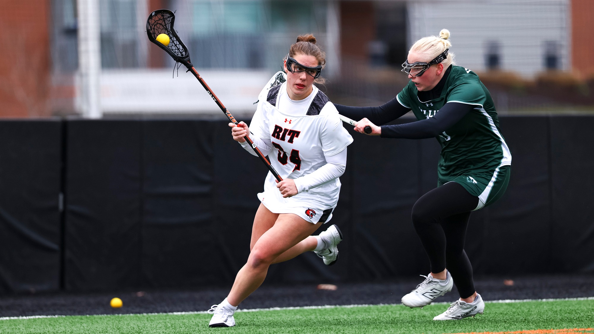A women's lacrosse player cradling the ball past her defender