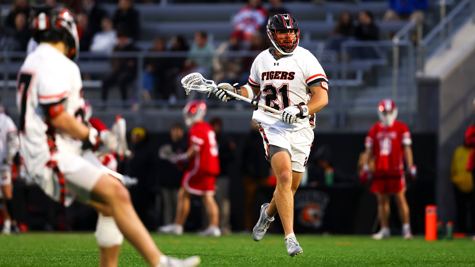 A men's lacrosse player cradles past a defender