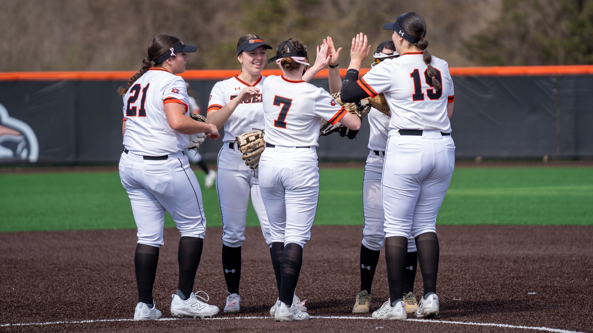 softball players high fiving on the mound