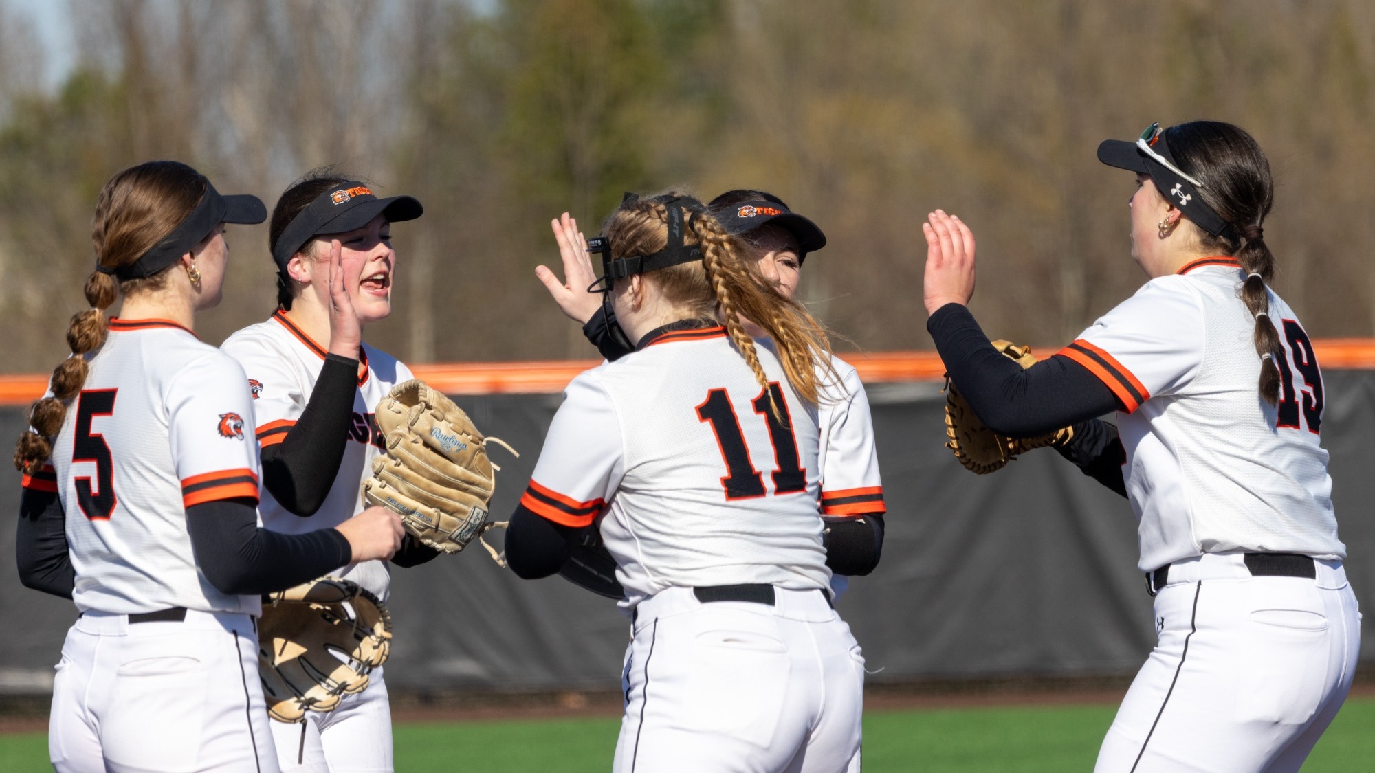 softball players high fiving on the mound