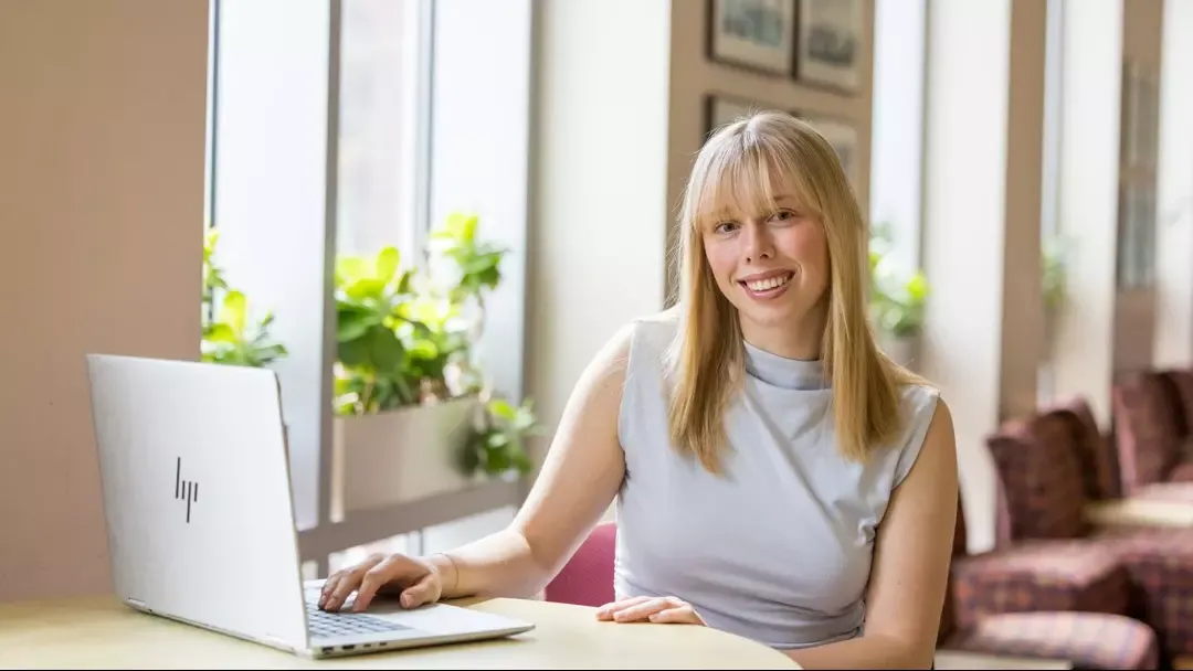a photo of Jillian Antol sitting at a desk in front of a laptop