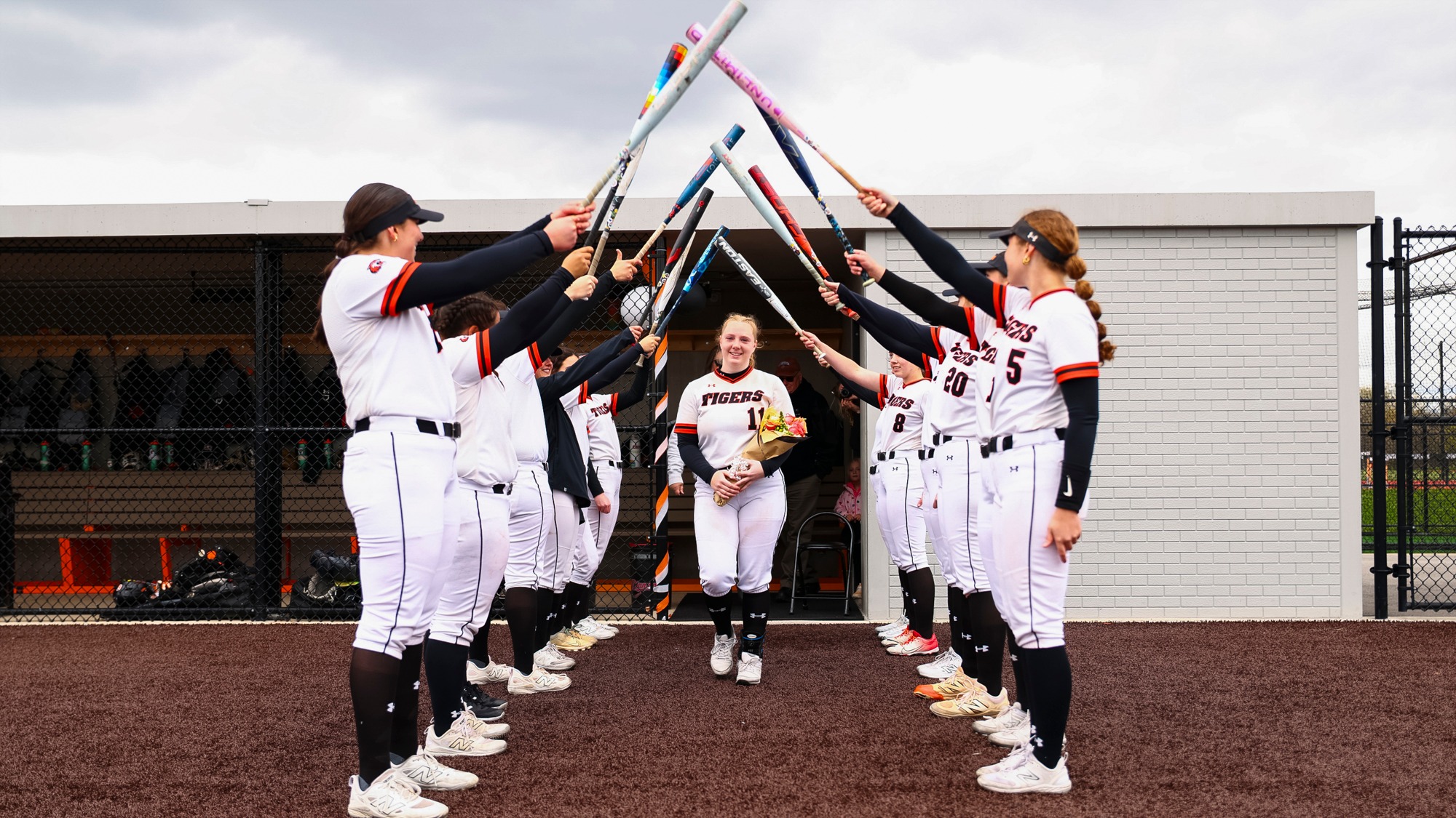 two rows of players make a bat tunnel for senior Jessica Majot to walk through on senior day