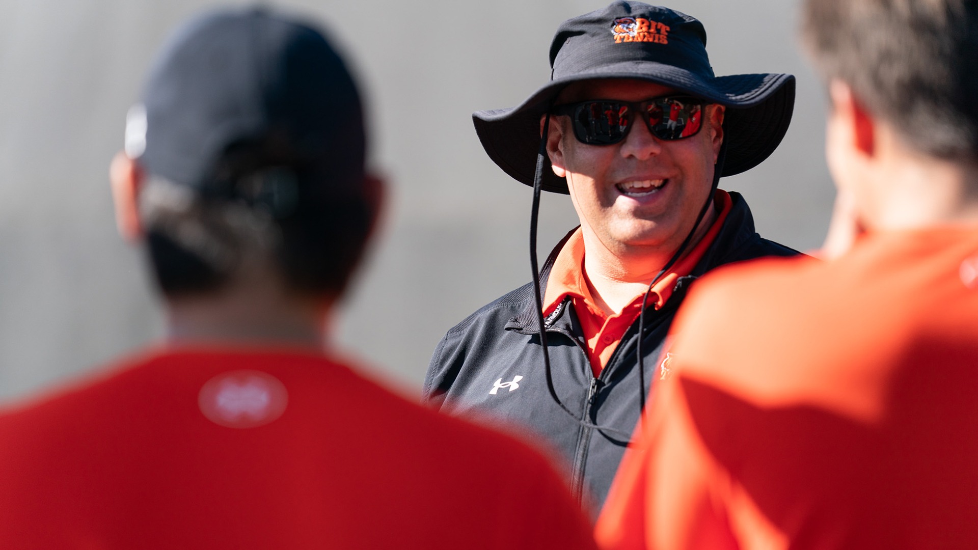 A photo of Tom Linhart coaching the tennis team at RIT