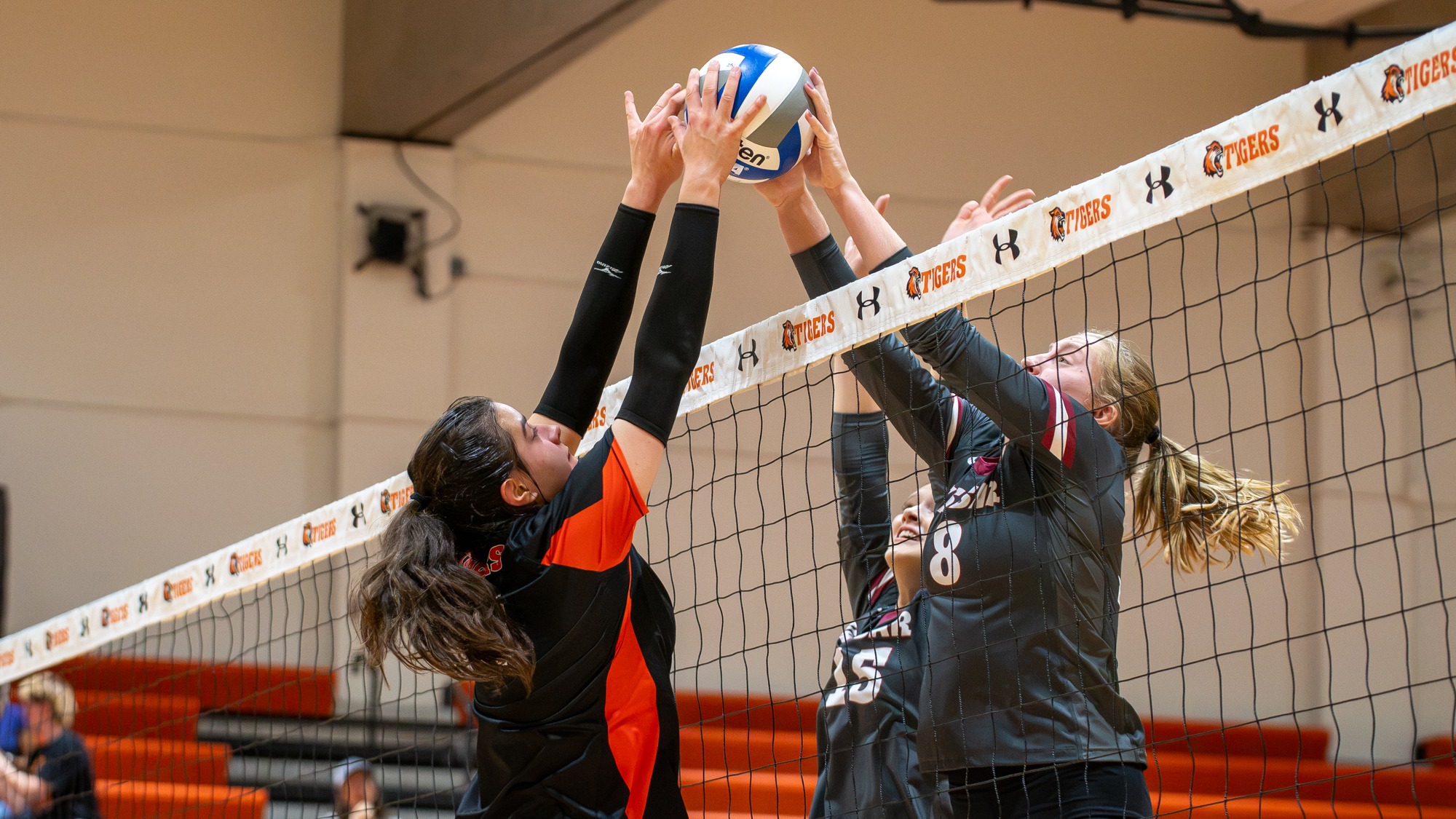 two women's volleyball players jousting at the net