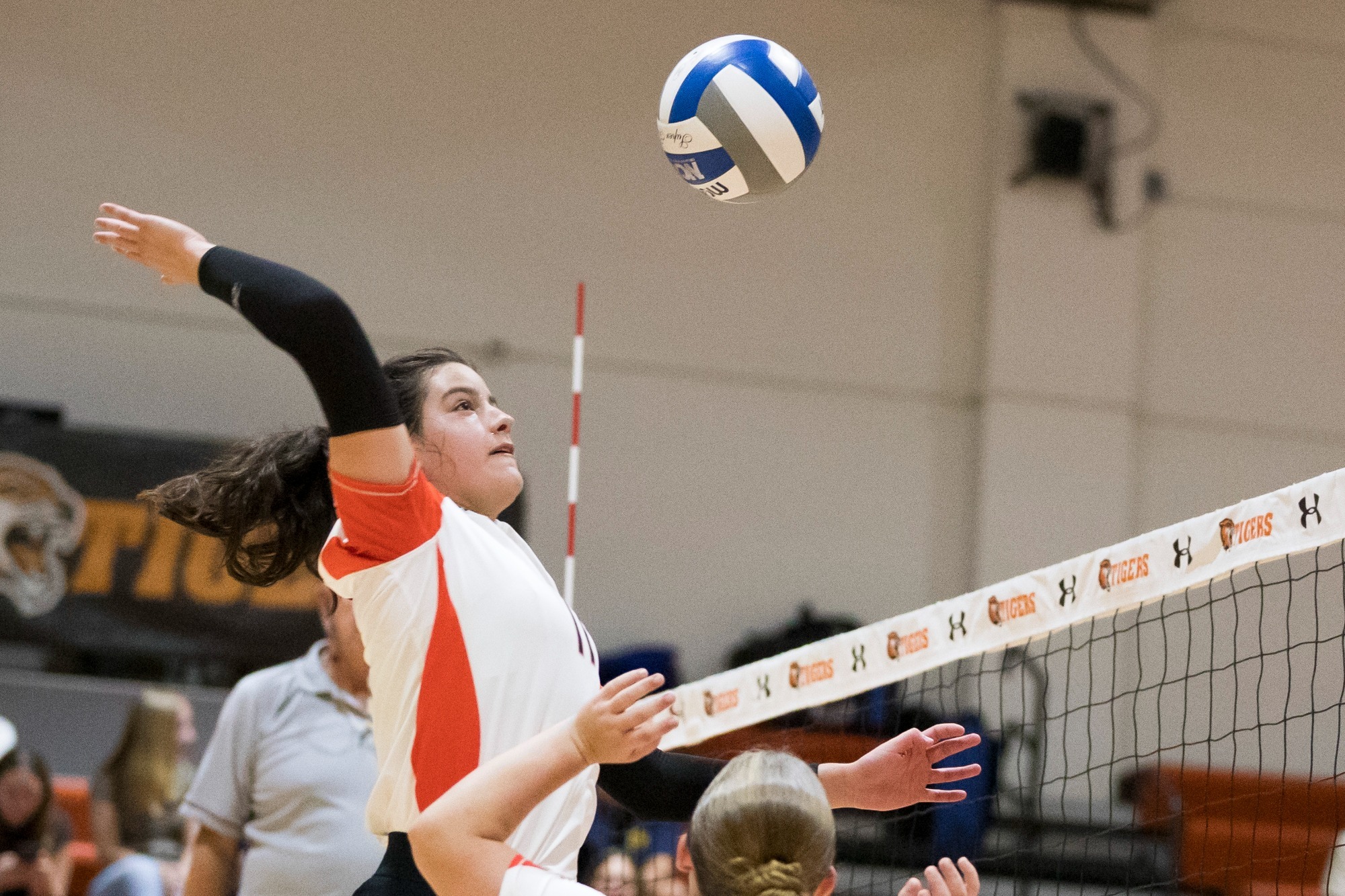 a women's volleyball player attacking at the net