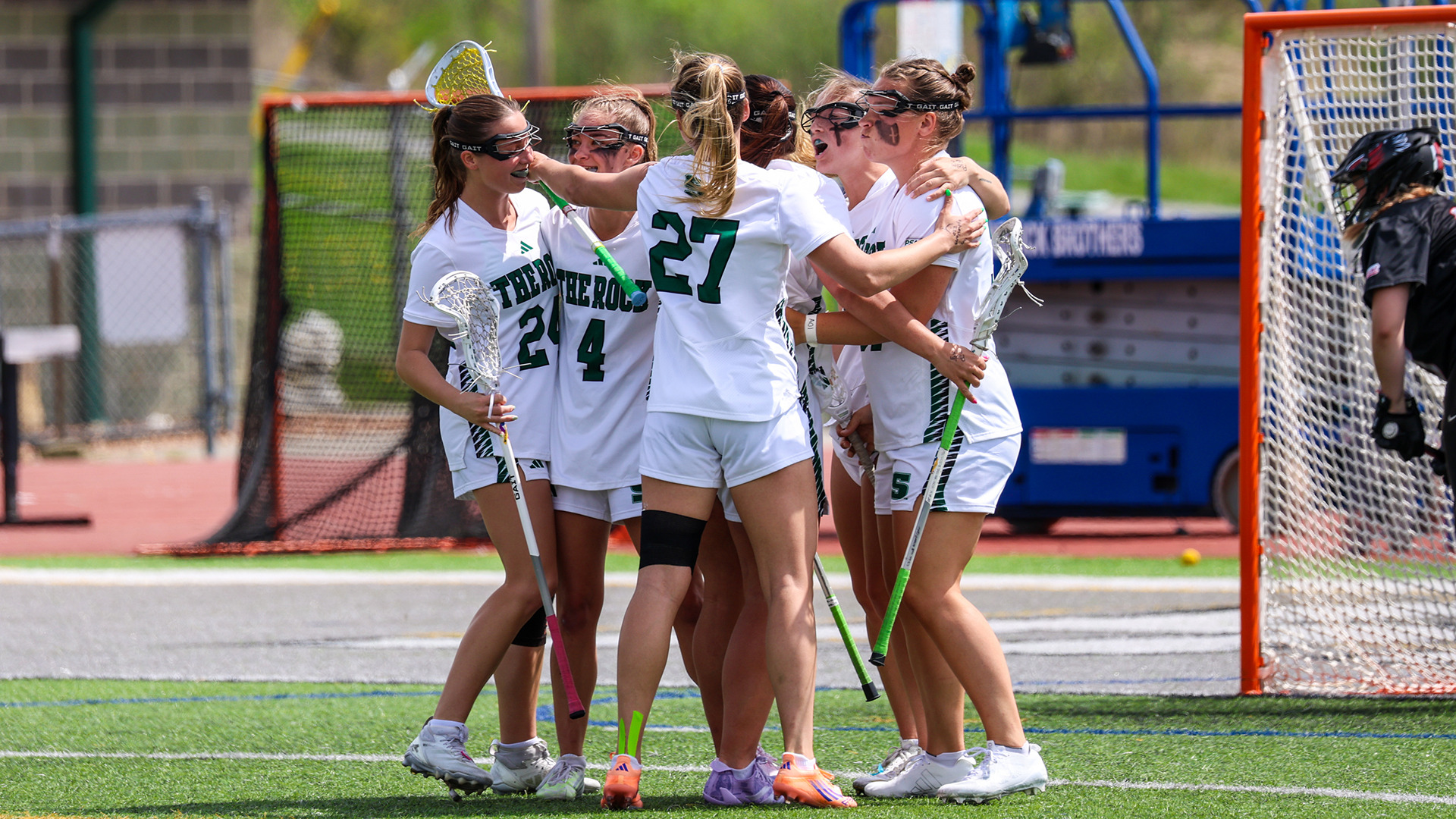 Members of the SRU lacrosse team huddle to celebrate a goal against IUP.