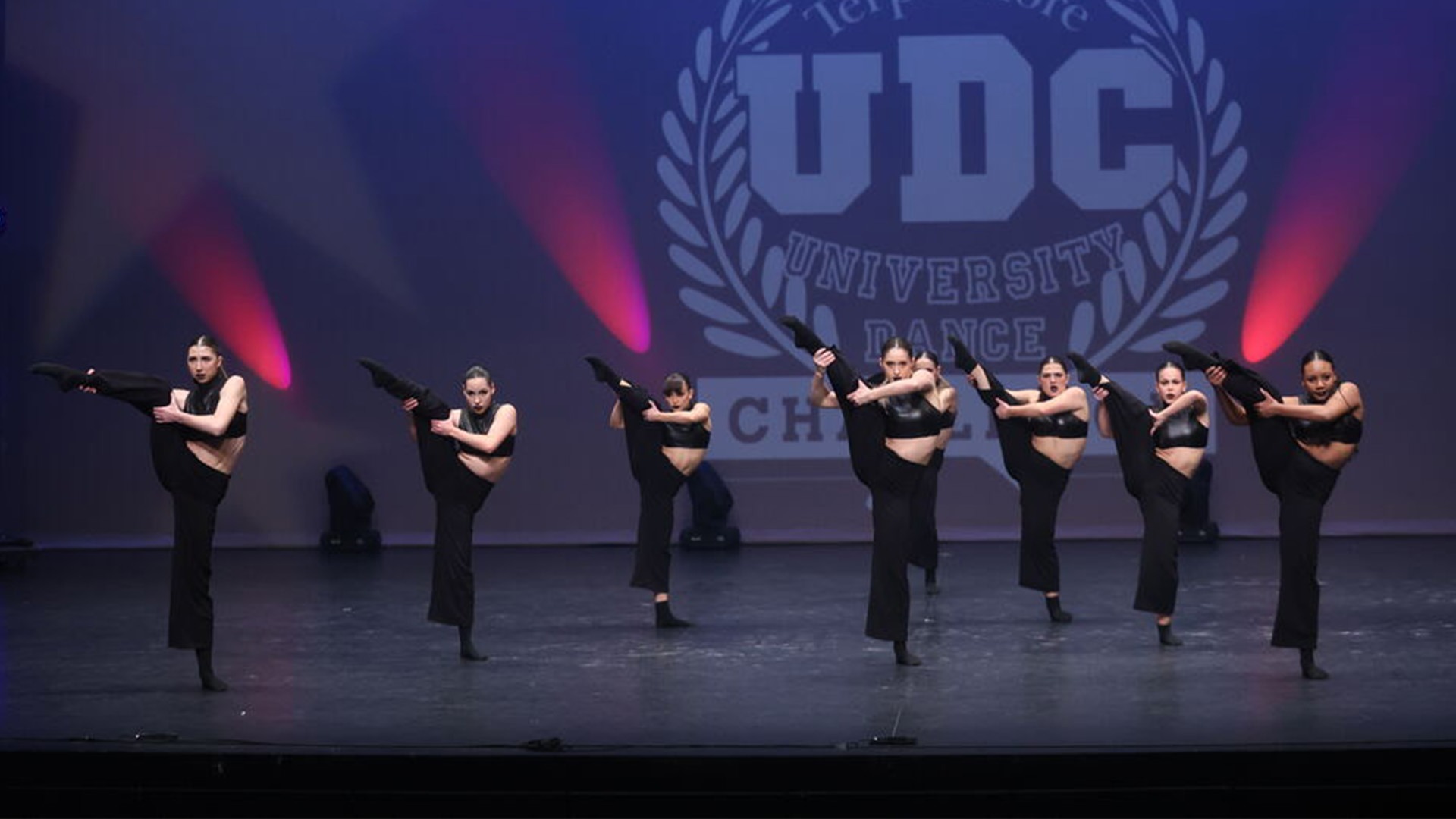 Eight dancers pose on stage during a routine.