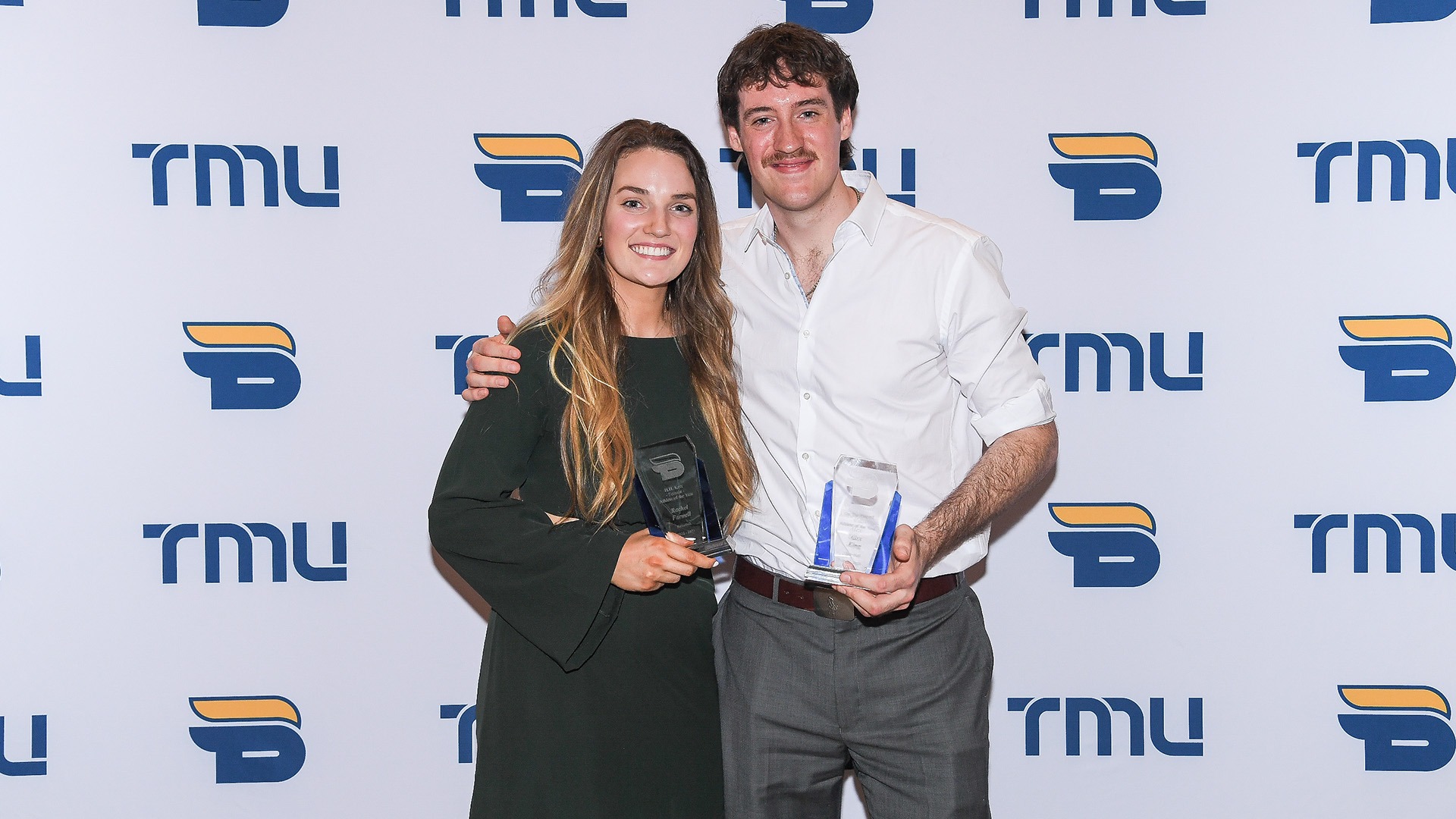 Two athletes pose with their Athlete of the Year awards against a TMU Bold back drop.