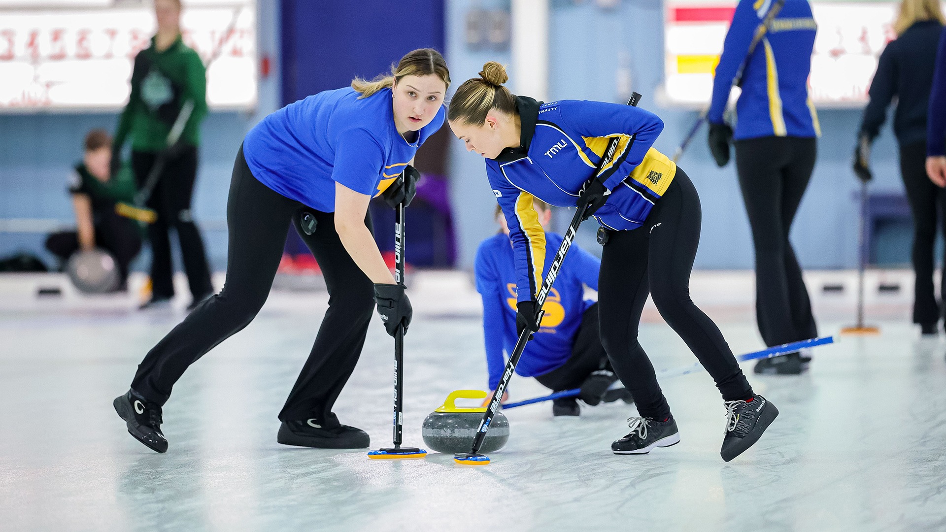 Two TMU curlers sweep a rock