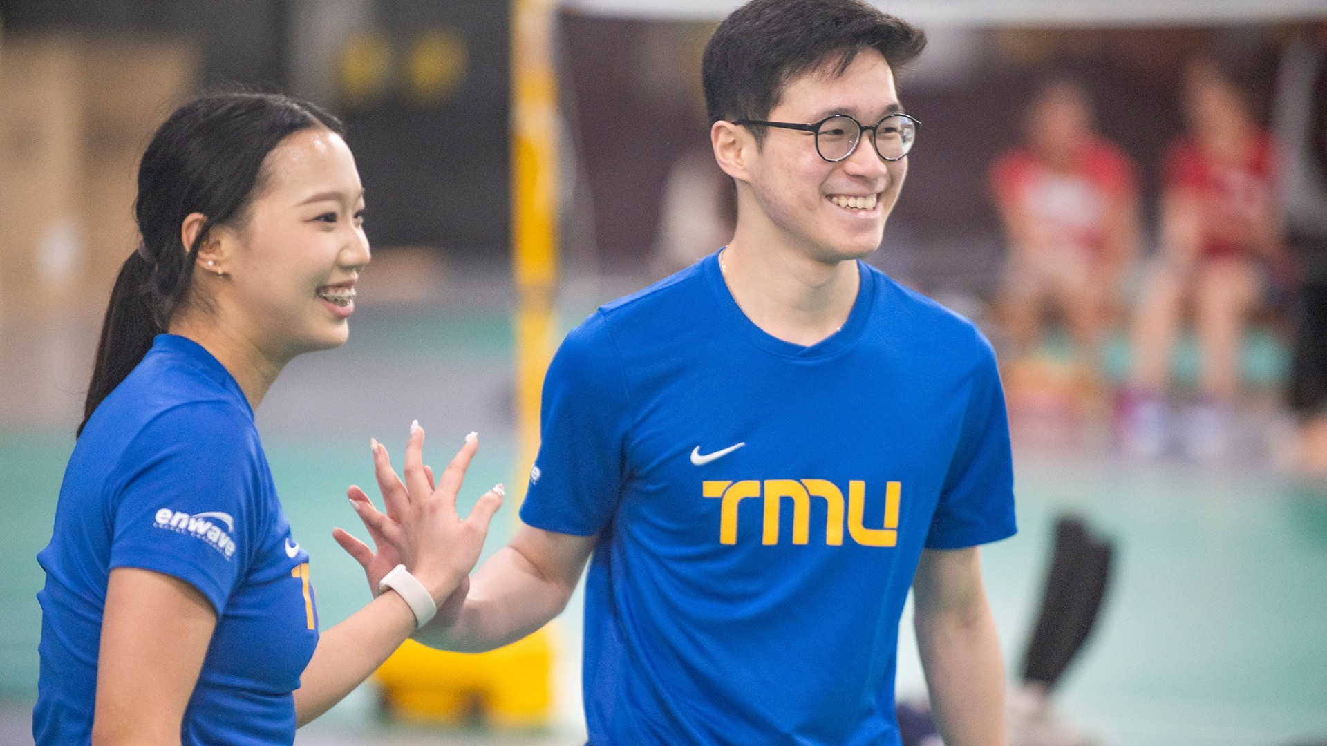 Two TMU players high five after a point while smiling