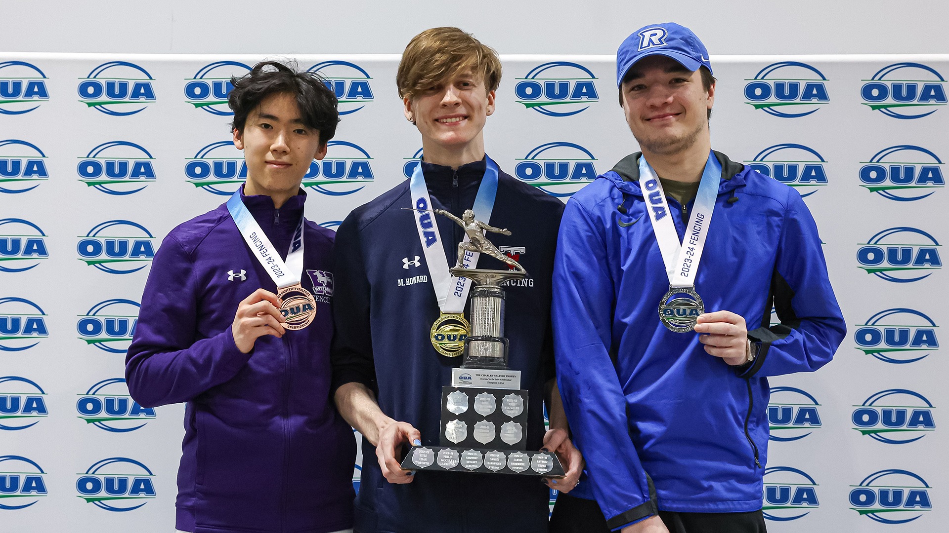 Three athletes pose on a podium with their championship medals
