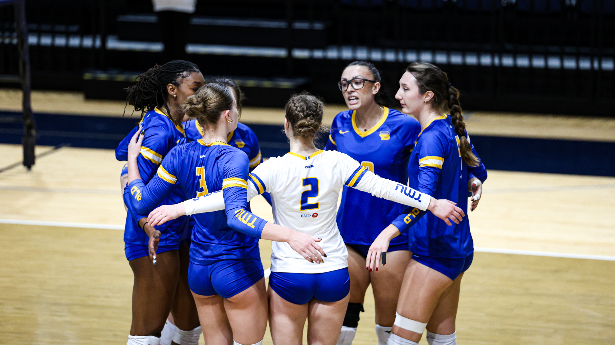 Bold women's volleyball players huddle after a point