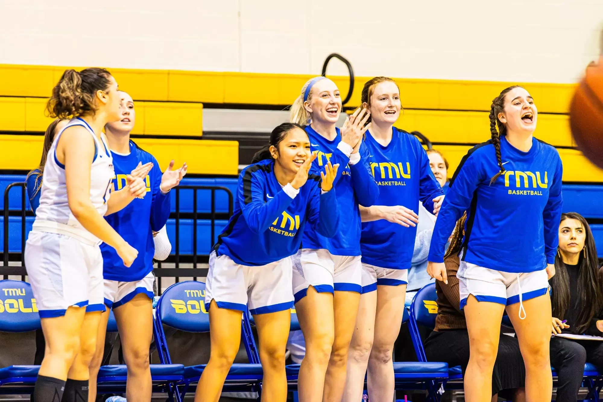 TMU Bold women's basketball bench celebrates after winning a point