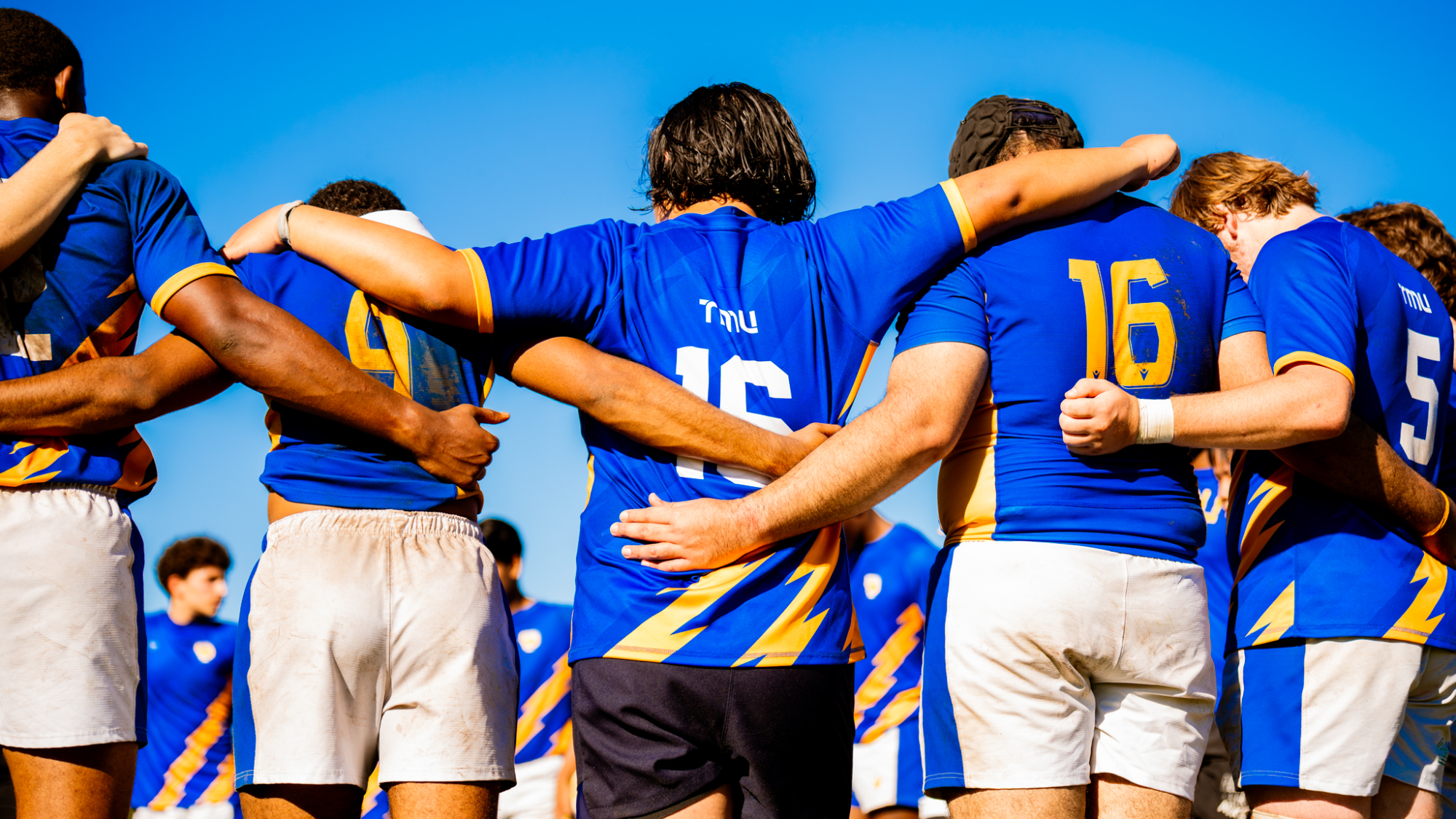 Rugby players put their arms around each other
