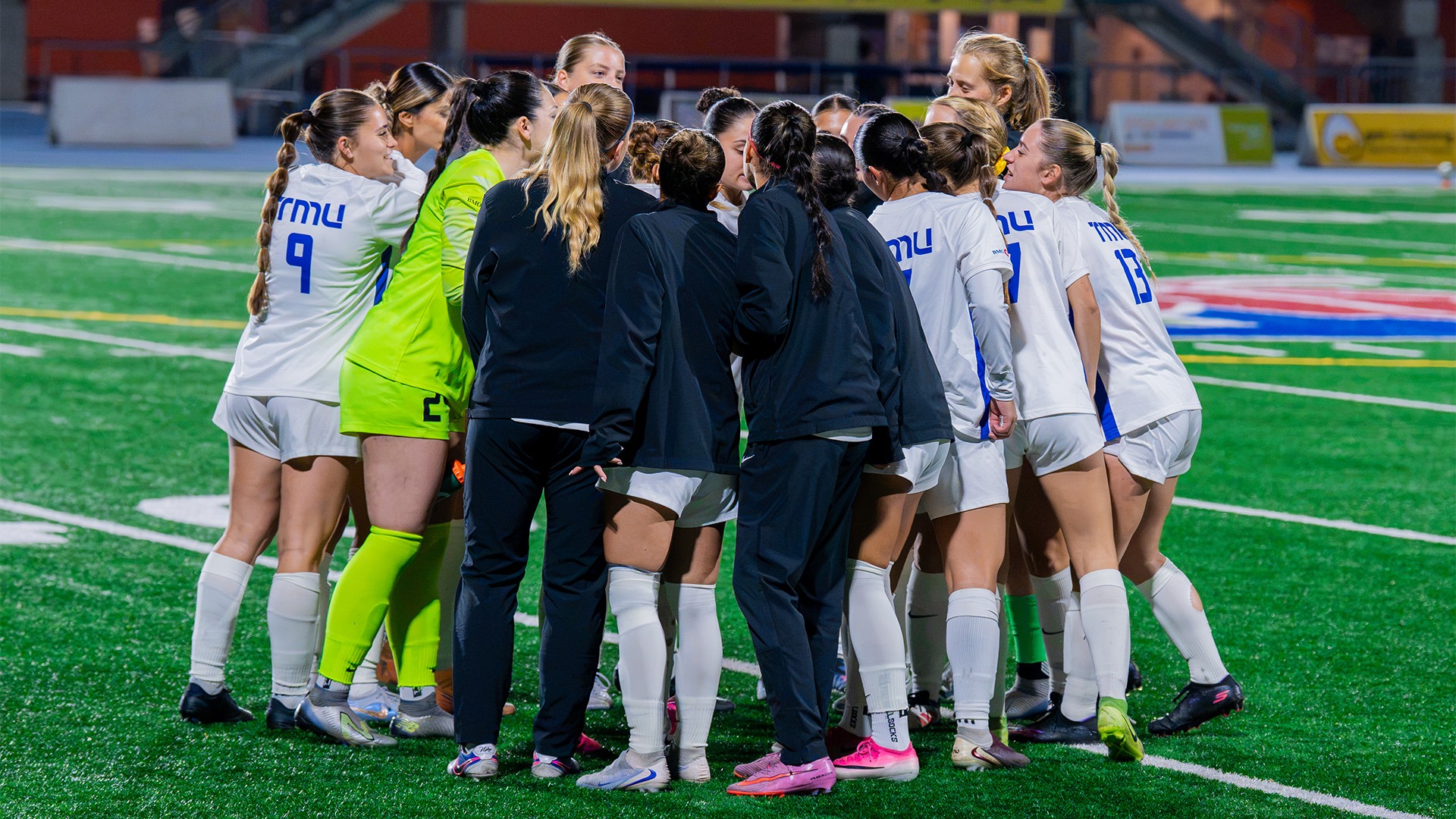 Bold women's soccer team in a post game huddle 