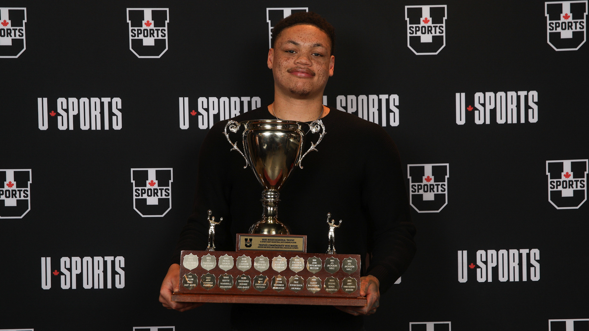 Aaron Rhooms smiles with the Mike Moser Trophy