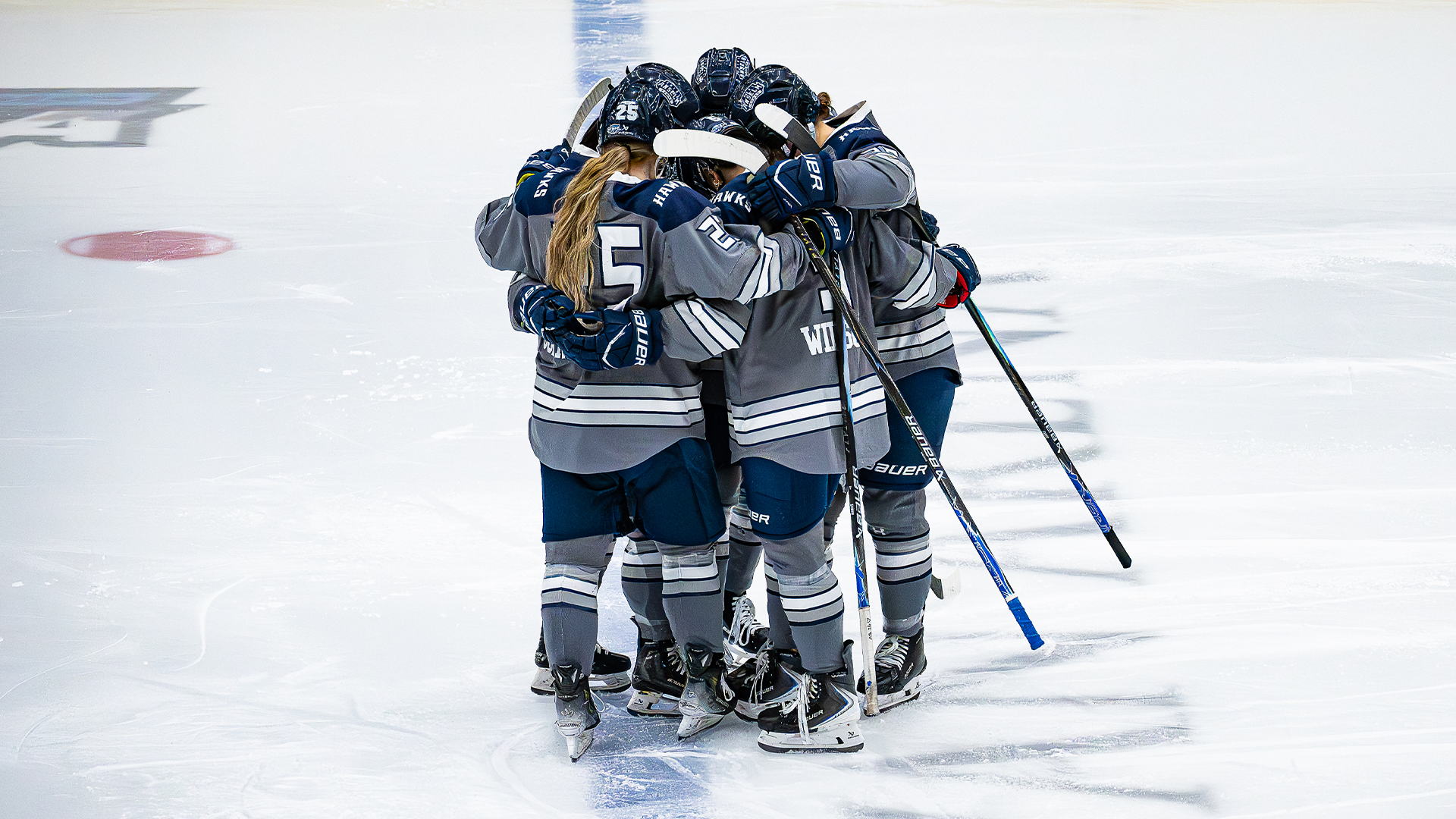 Women's ice hockey team members huddle before faceoff