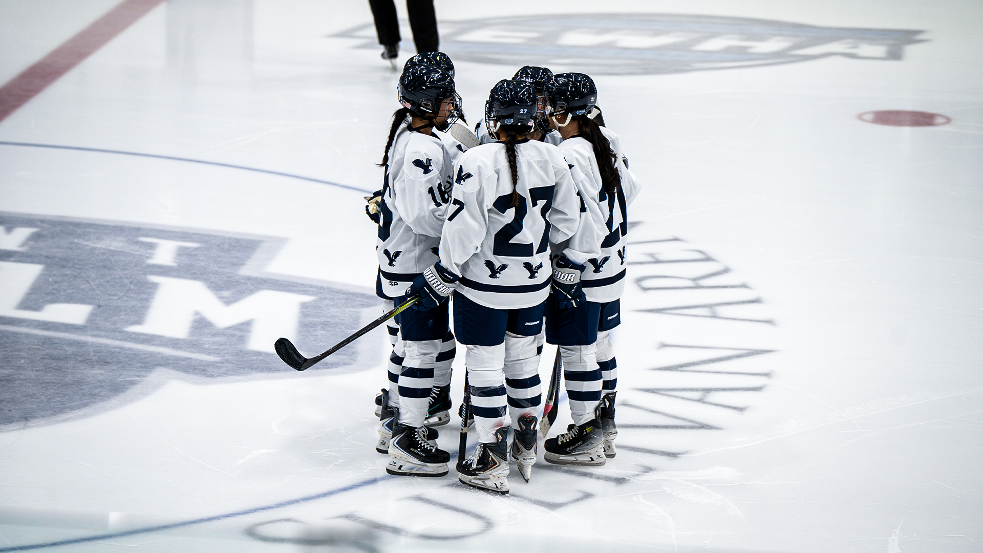 Women's ice hockey players huddle before faceoff