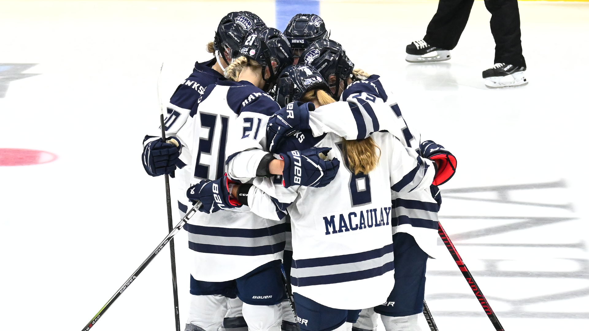Women's ice hockey players huddle before faceoff