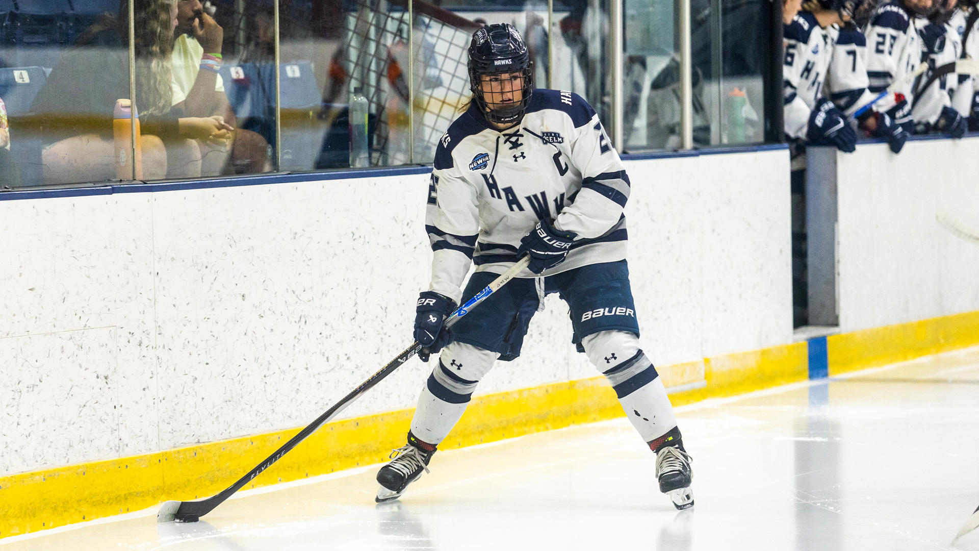 Brooklyn Schneiderhan skates down boards with puck