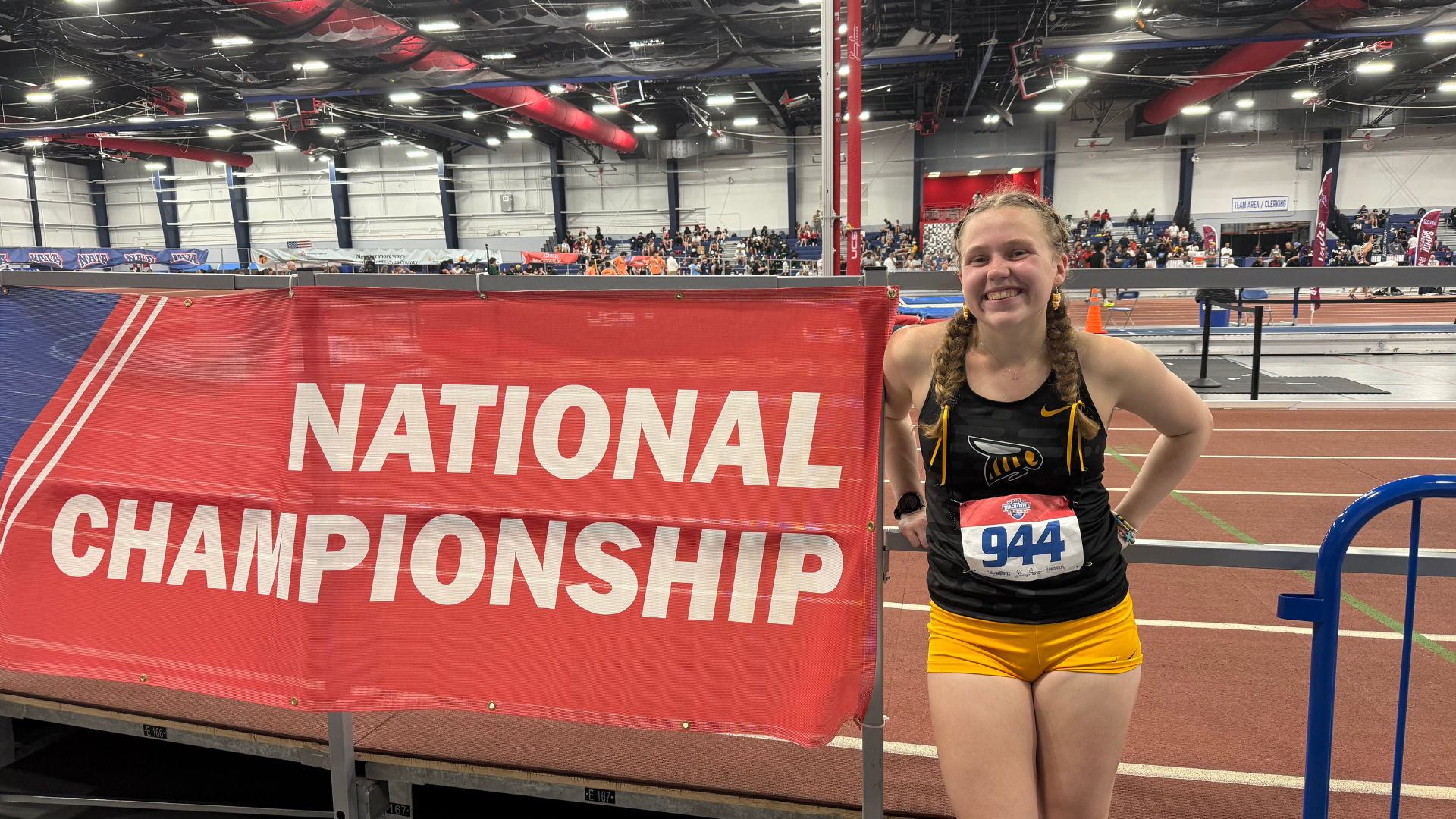 Ashlyn Vanlandingham poses with the NAIA Nationals banner after her race in the 1K.