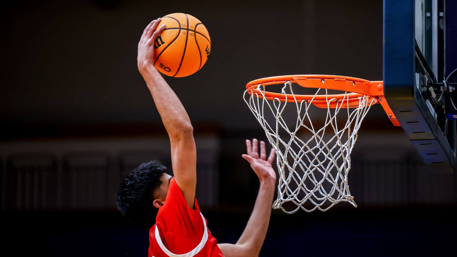 An SFU Men's Basketball player mid-air, about to dunk the ball. 