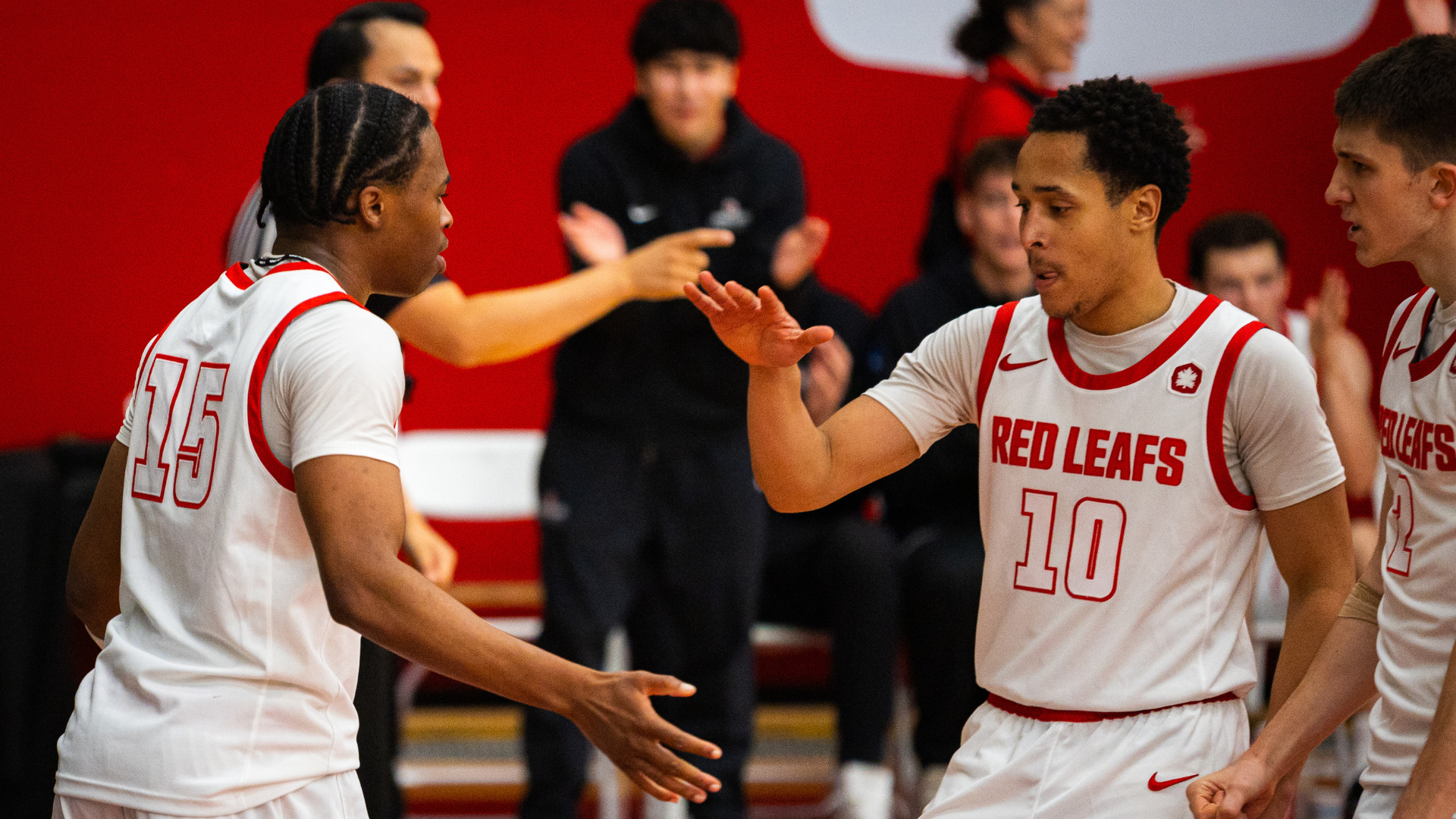 SFU Men's basketball players high five on the court.
