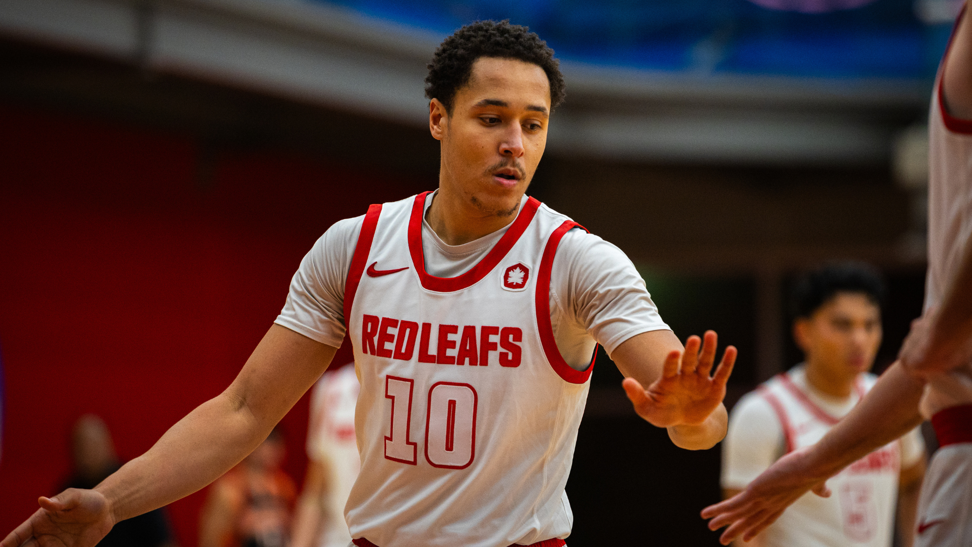 Men's Basketball player Daniel Smith high fives another player on the court