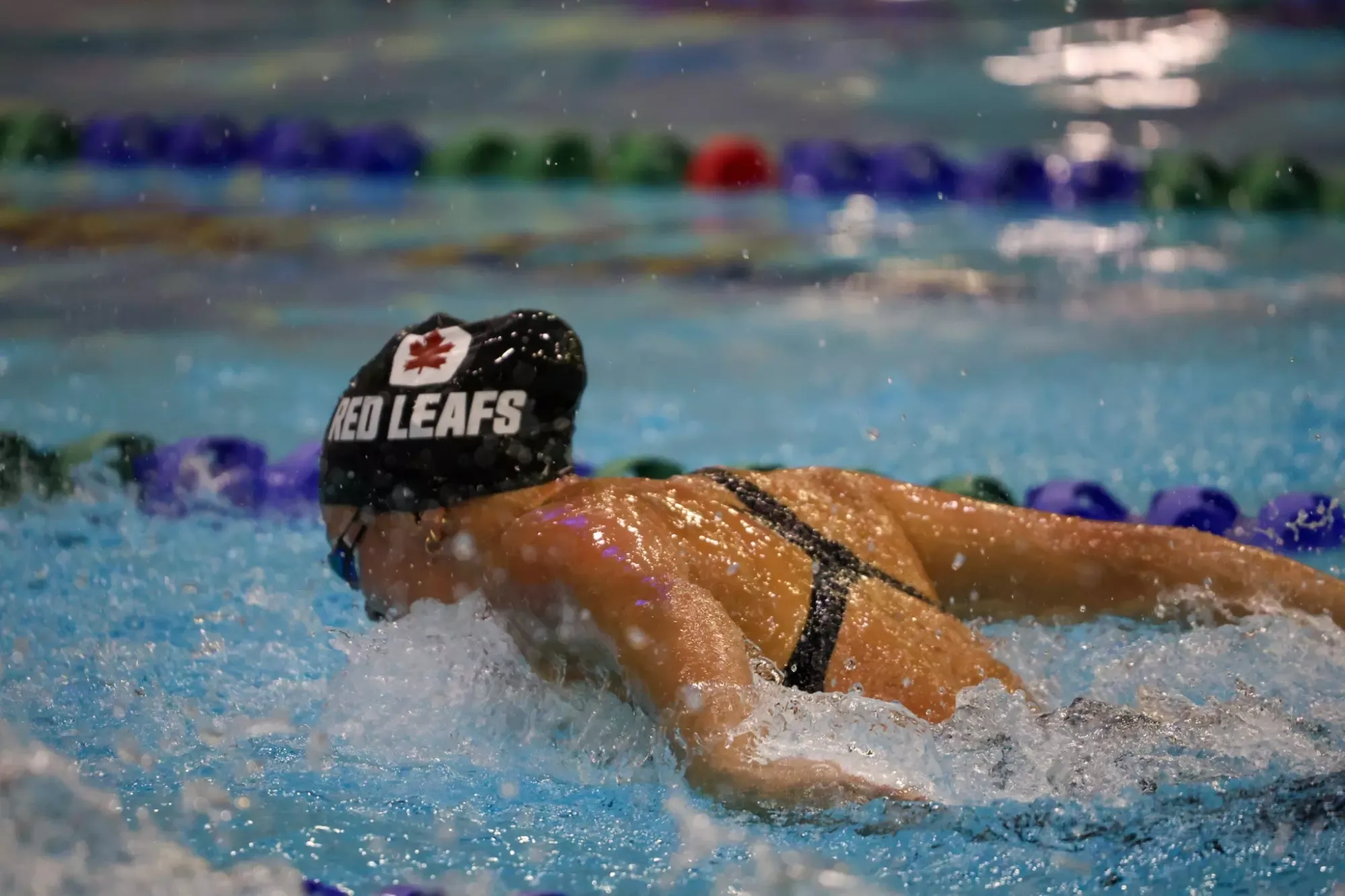 An SFU Women's Swimming athlete in the pool mid fly stroke