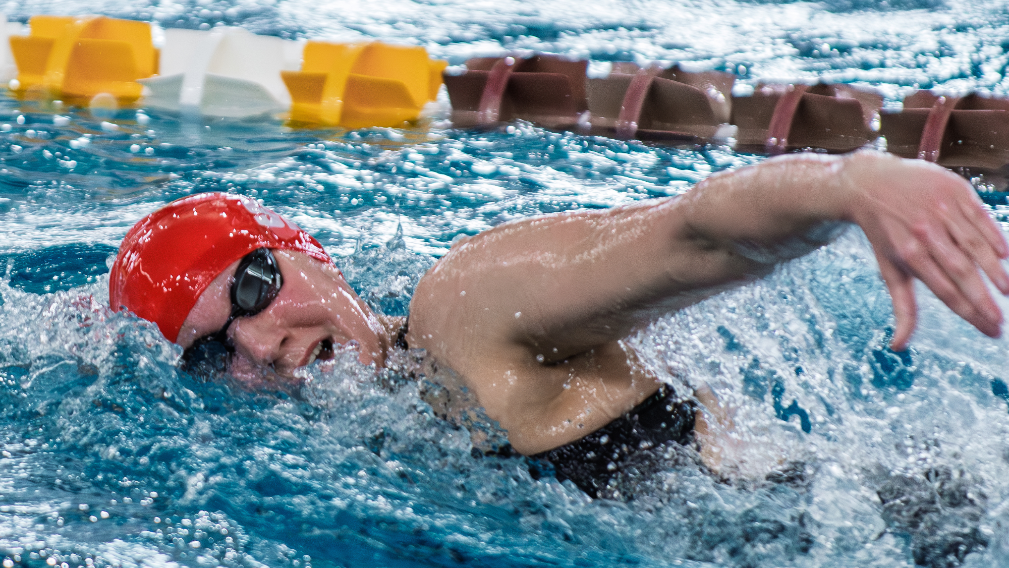 An SFU Women's Swimming student-athlete in the water mid-front stroke. 