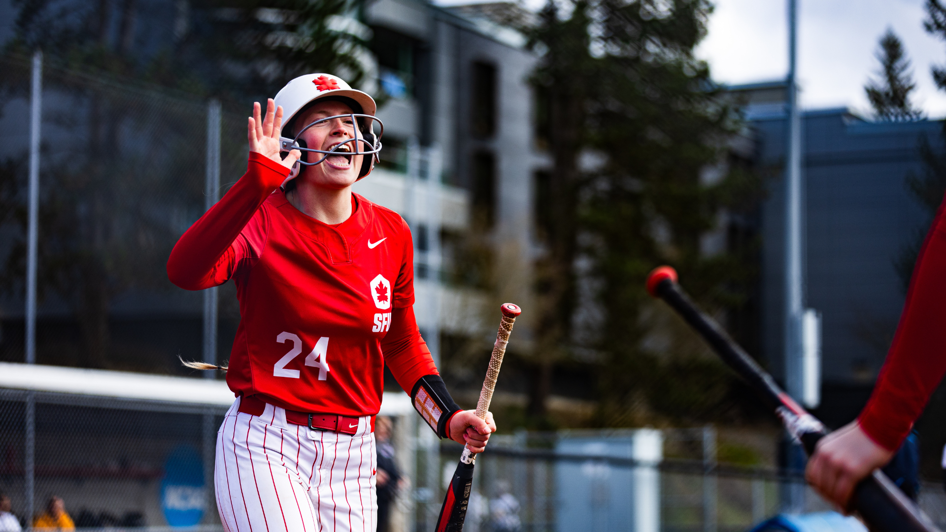 Softball player Ella Booth smiles and holds up a high five for another player