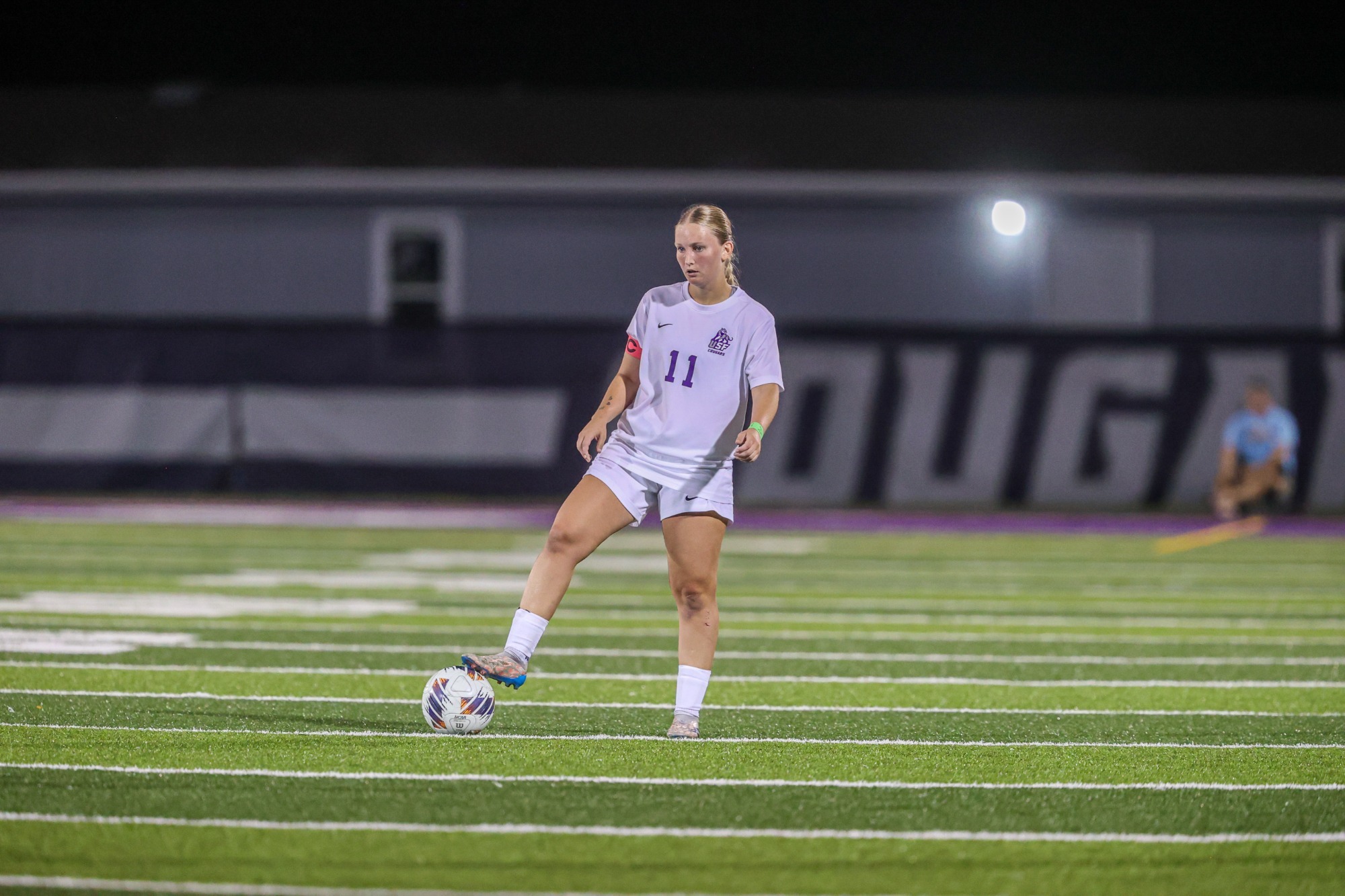 Women's soccer player holds ball under her foot while waiting for free kick