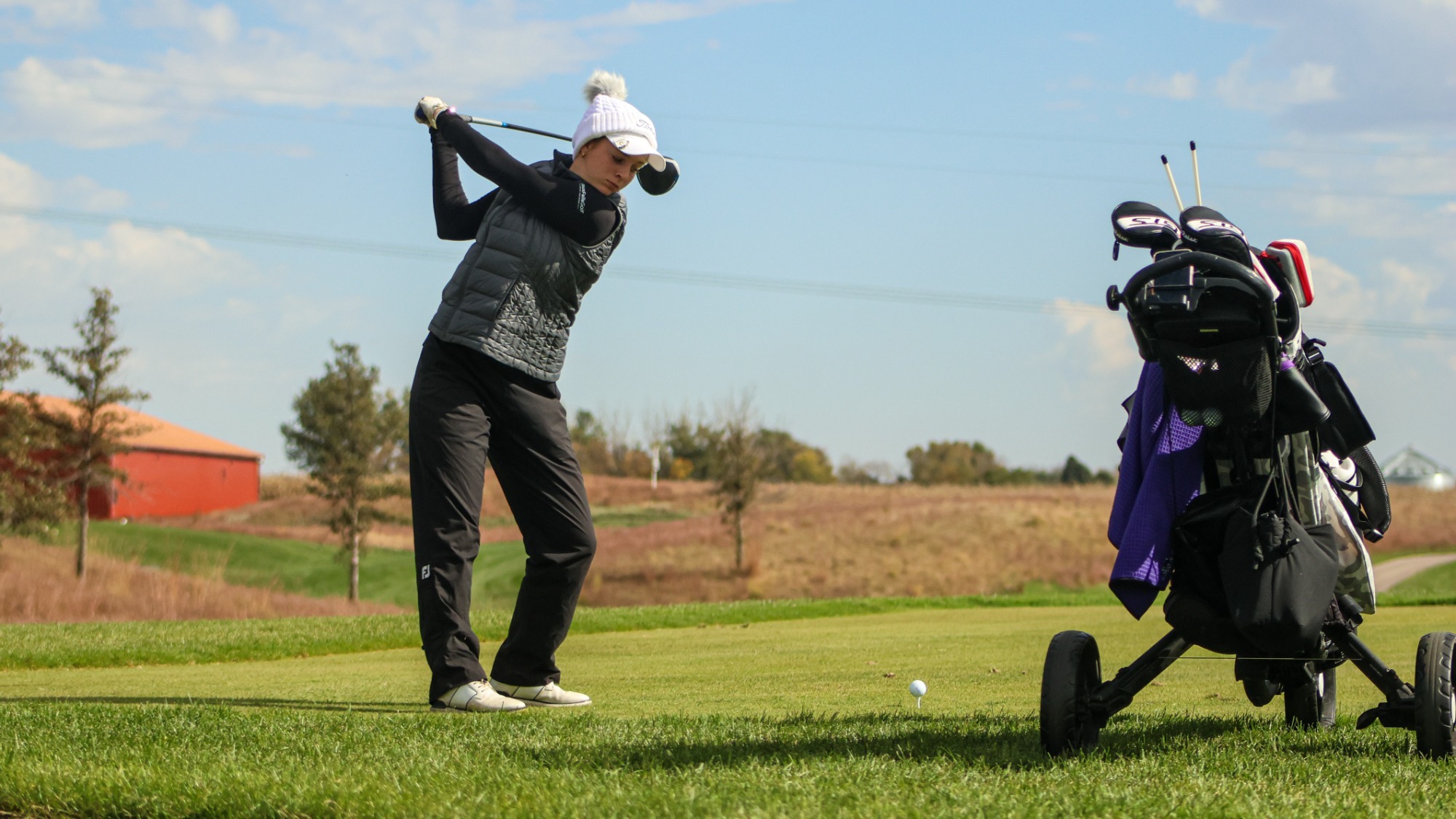 Women's golfer swinging at ball on the tee box