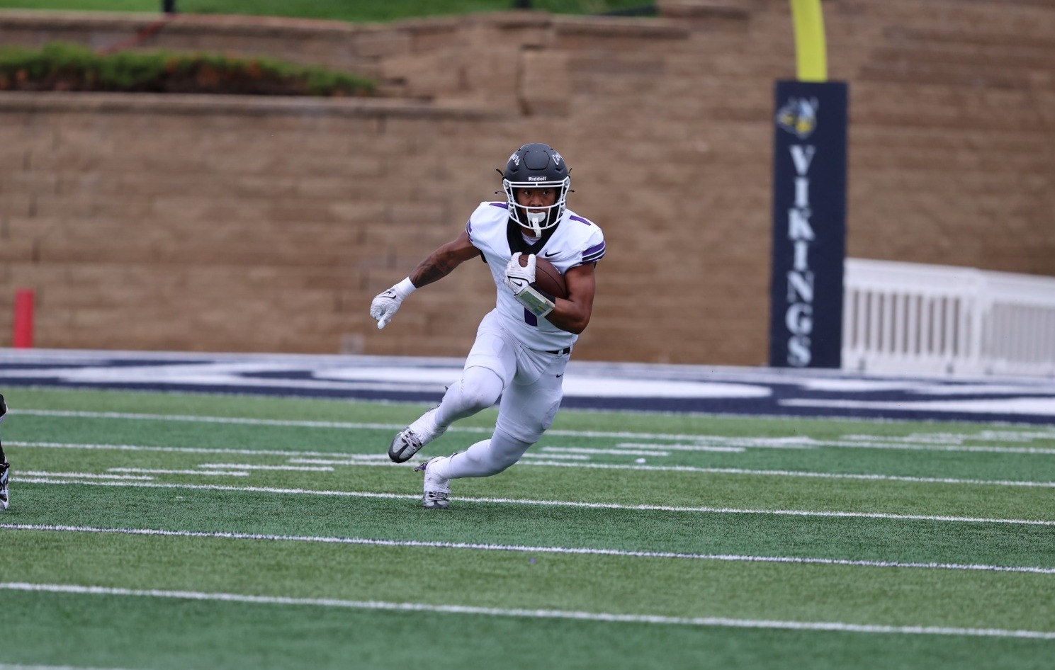 A USF football player carries the ball across the field while following a blocker during a road game against Augustana.
