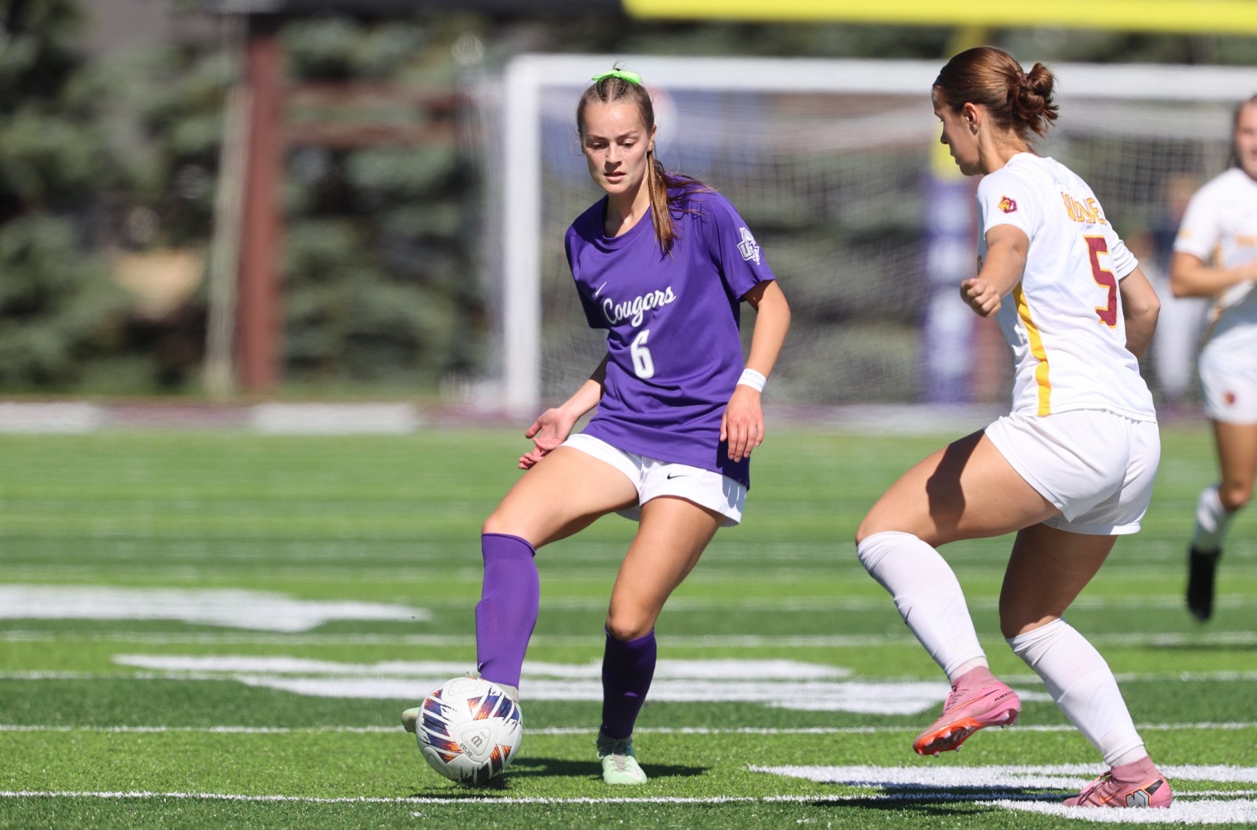 A women's soccer player controls the ball as a  defender closes in