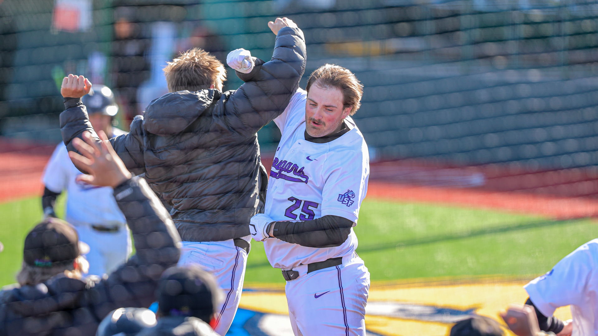 Brady Schafer jumps and crosses arms with teammates after home run