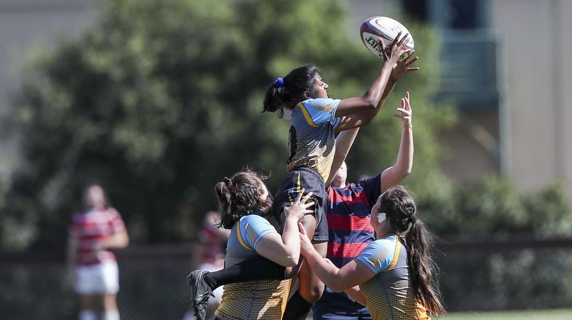 Player is lifted up by two other players to catch the rugby ball