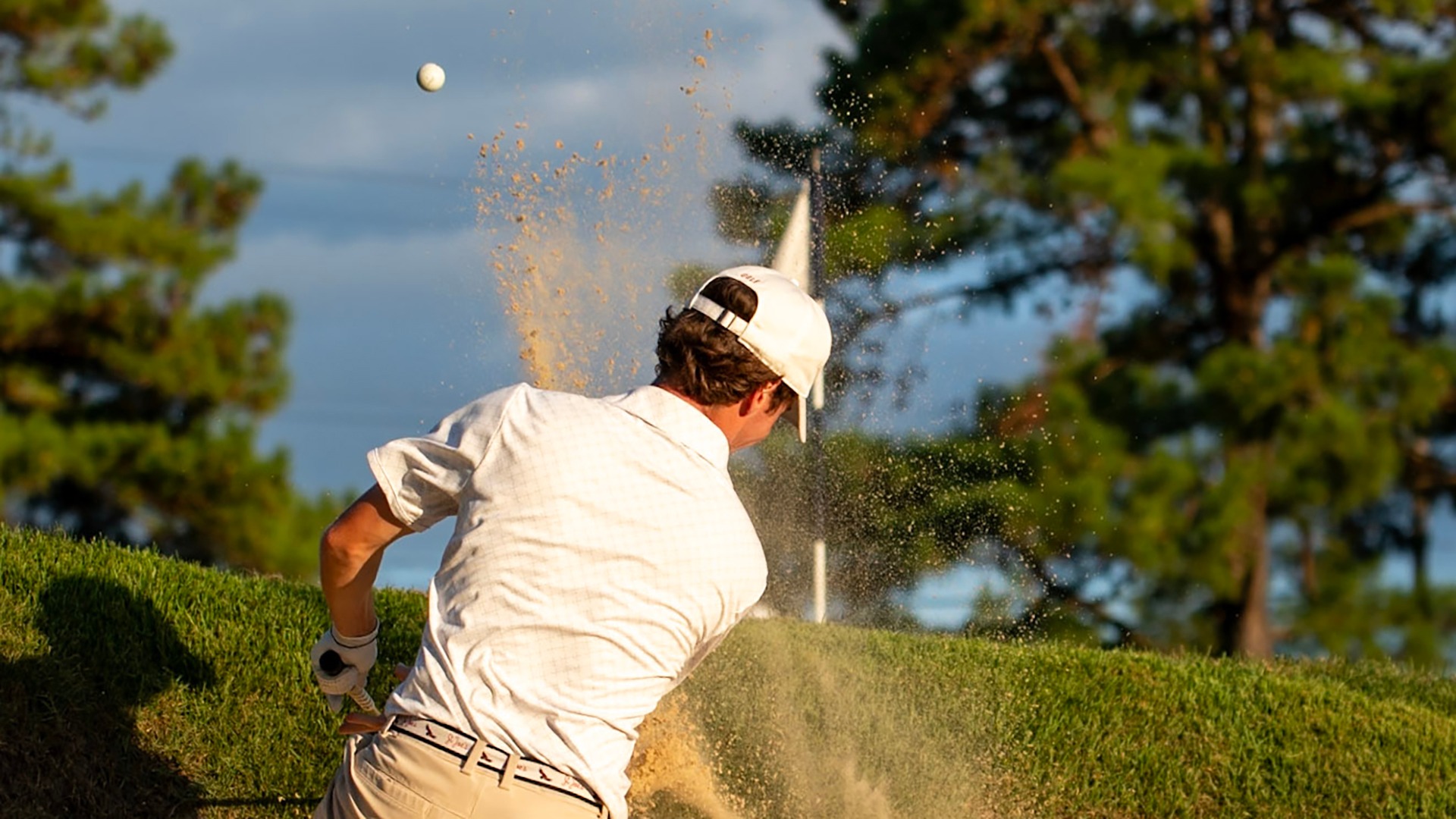 Hawk men's golfer chips from the bunker.