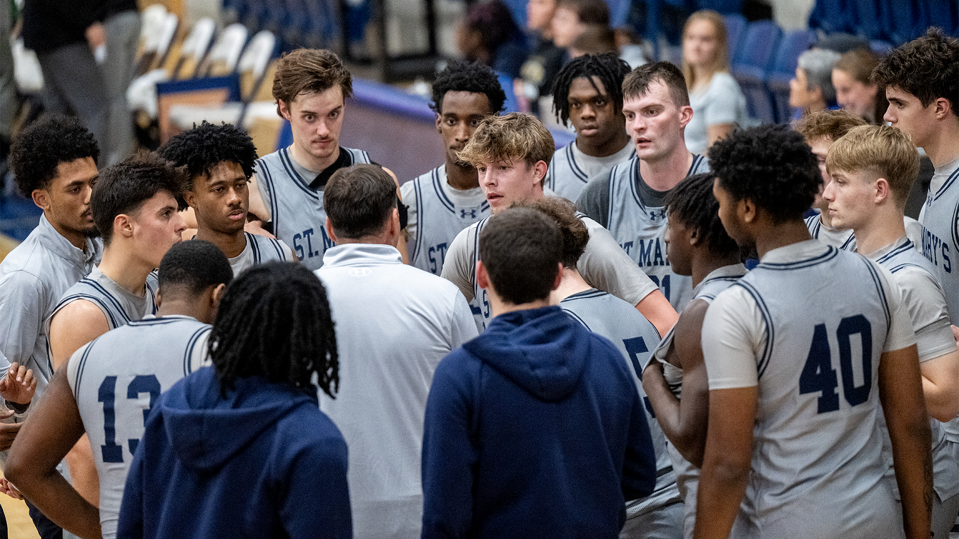 Head Coach Chris Harney surrounded by team during a timeout against Regent on Dec. 12, 2025