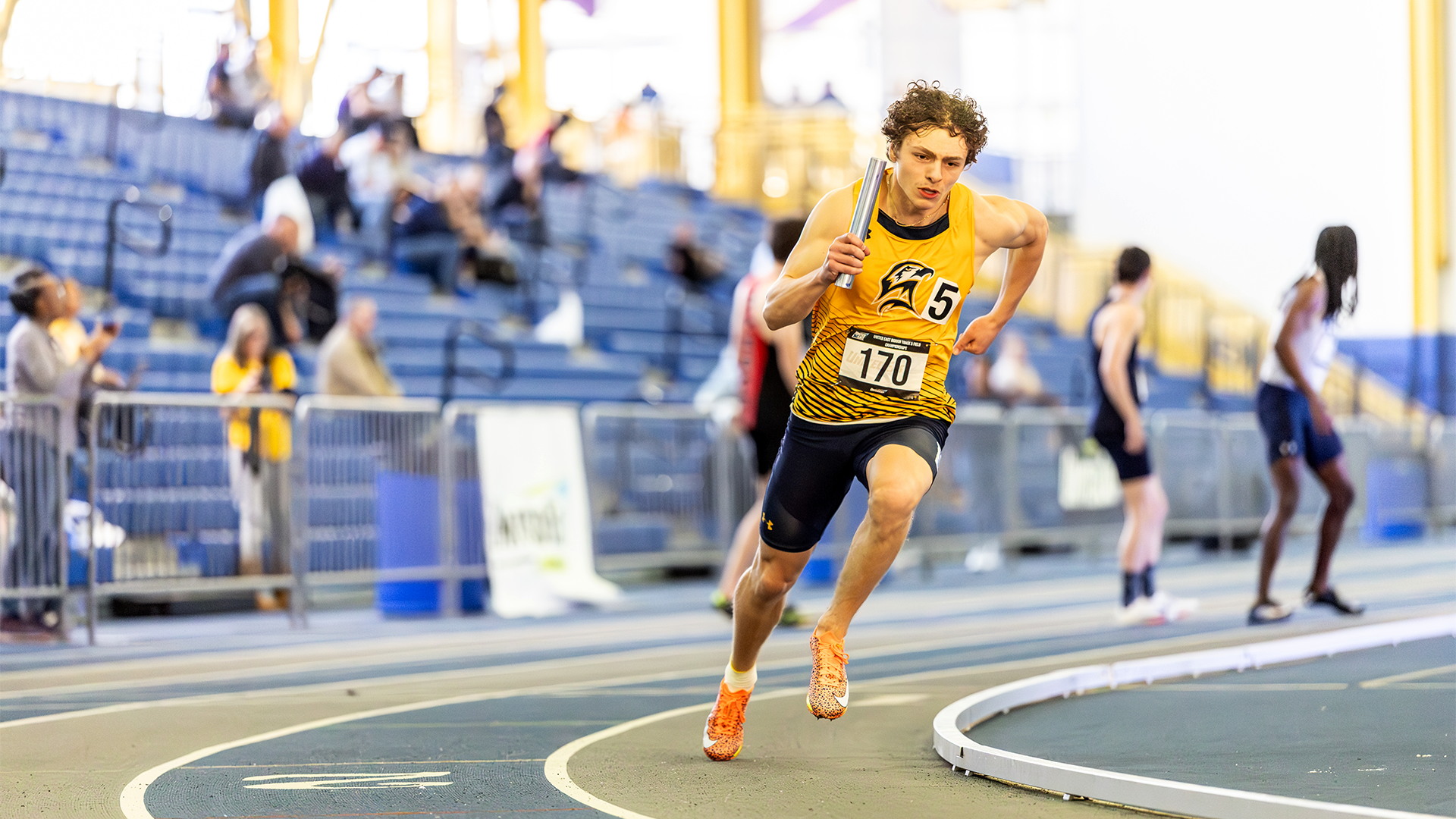 Collin Fitzgerald holding a baton and rounding the corner at the 2025 United East Indoor Track and Field Championships on February 28.