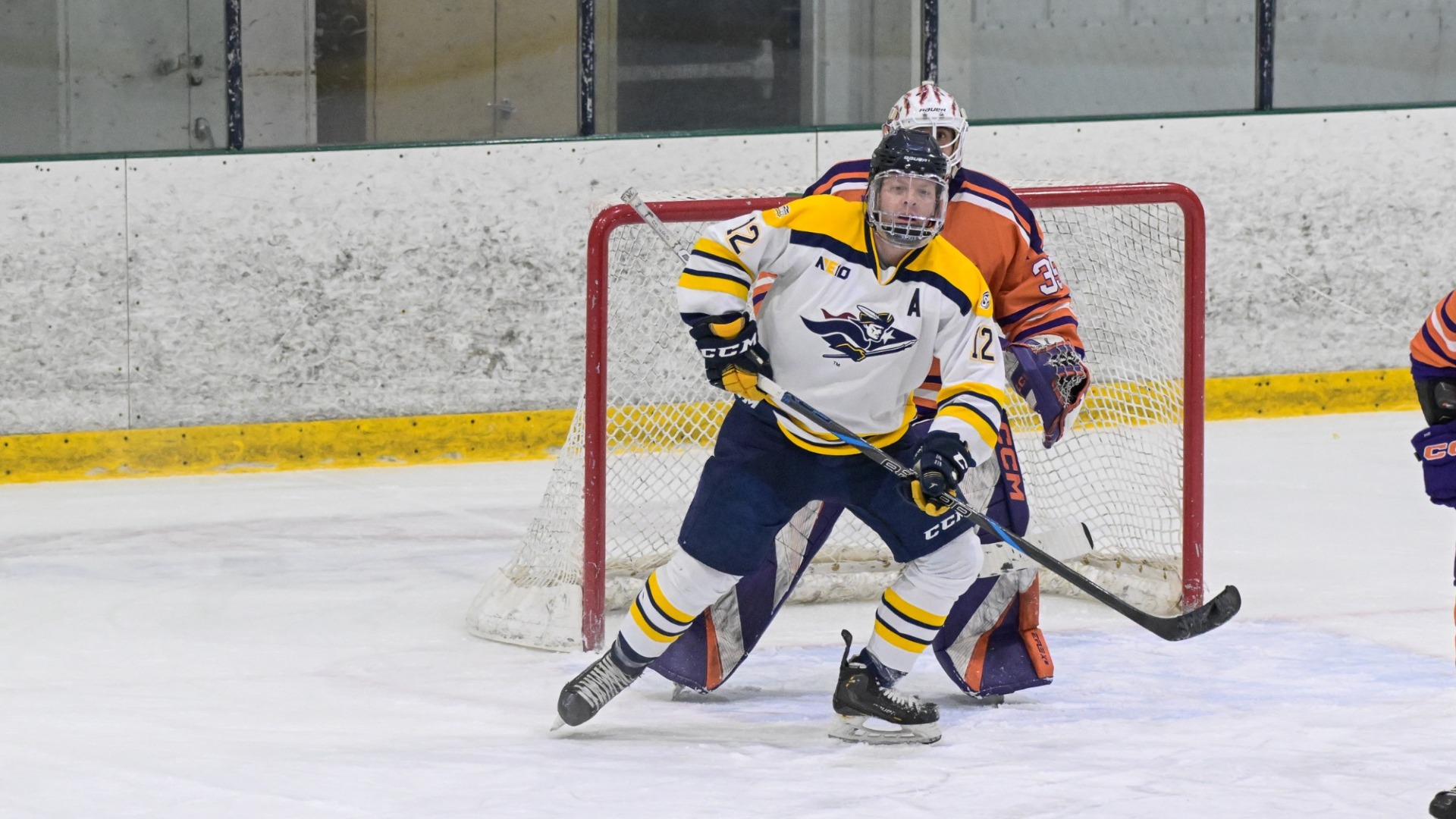 Ice hockey assistant captain Ryan Pomposelli is shown in front of the net waiting for a scoring chance