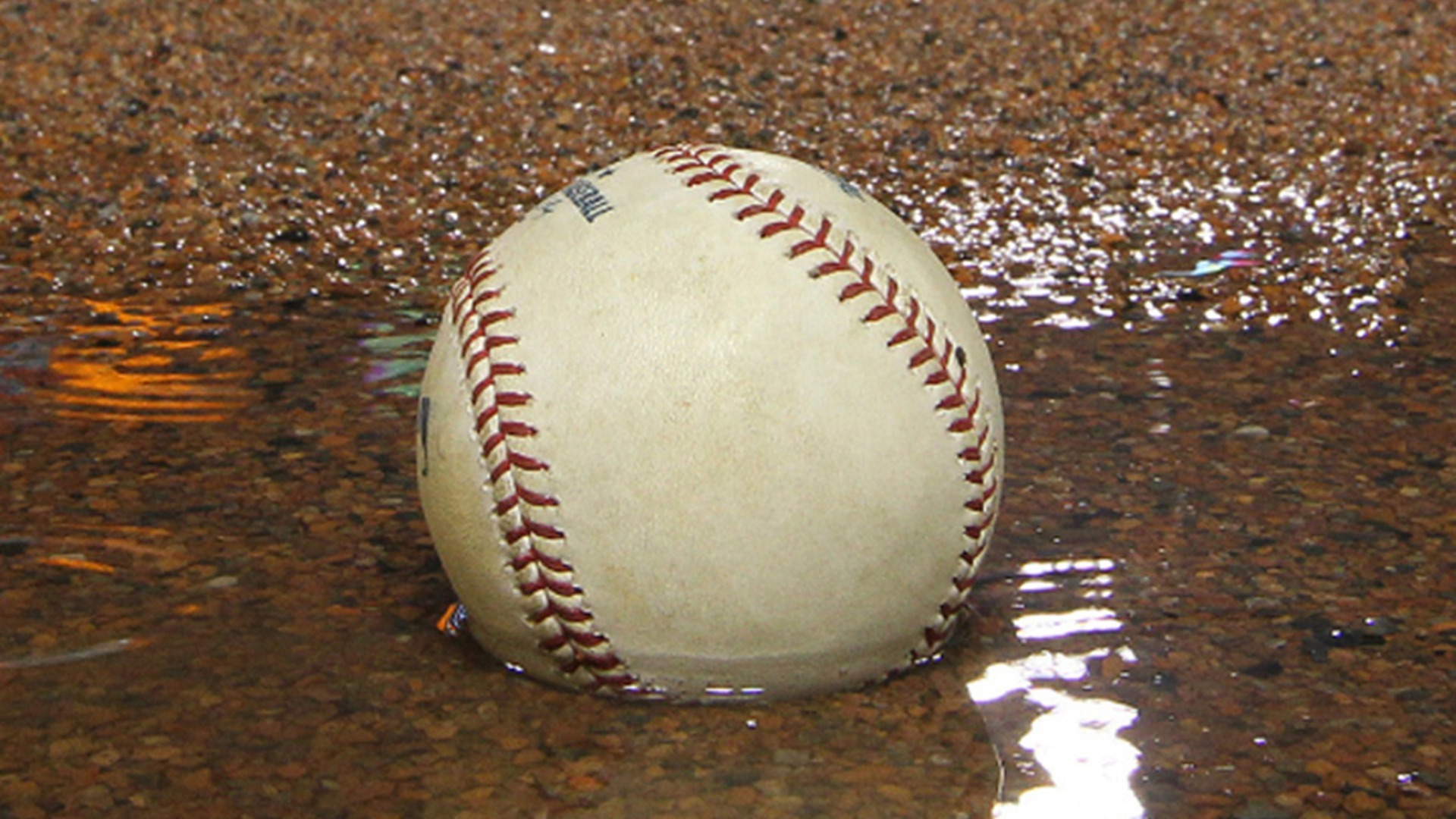 a baseball in a puddle on the infield